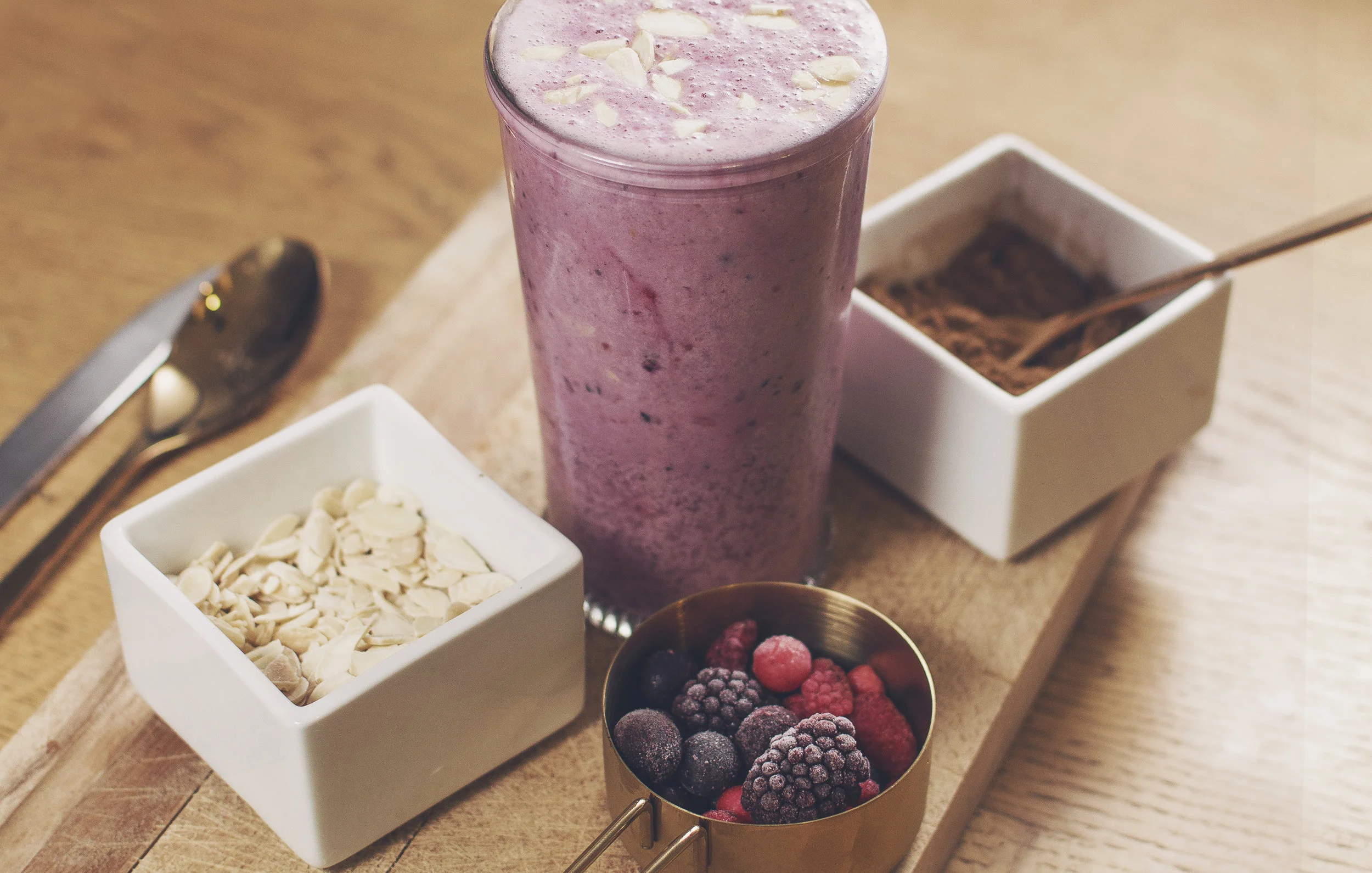 Berry protein shake on a wooden table with berries and almonds