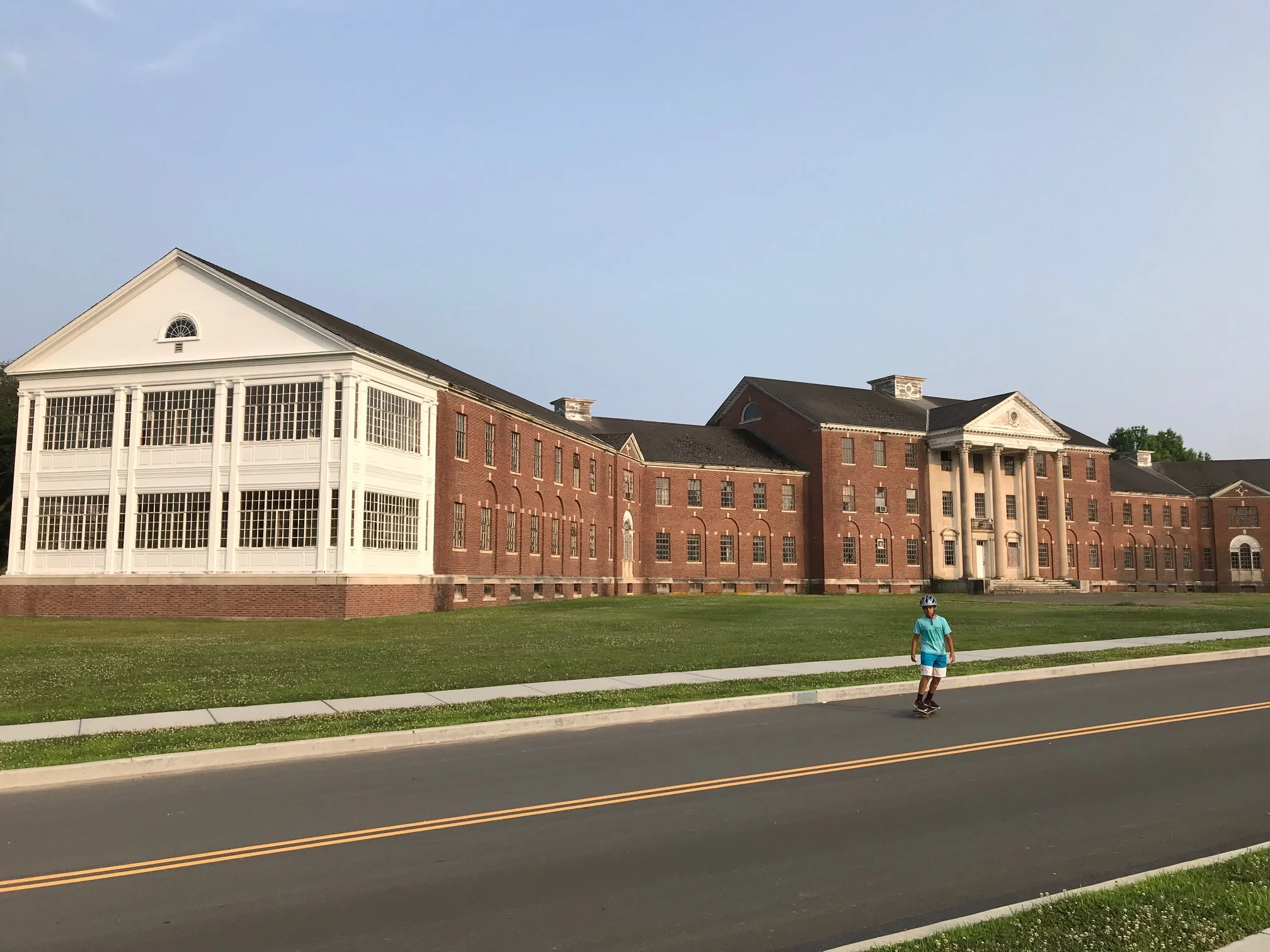 Oblivious to its former purpose, a boy glides by the largest building on campus. The solariums on the ends were the activity rooms for volunteers.
