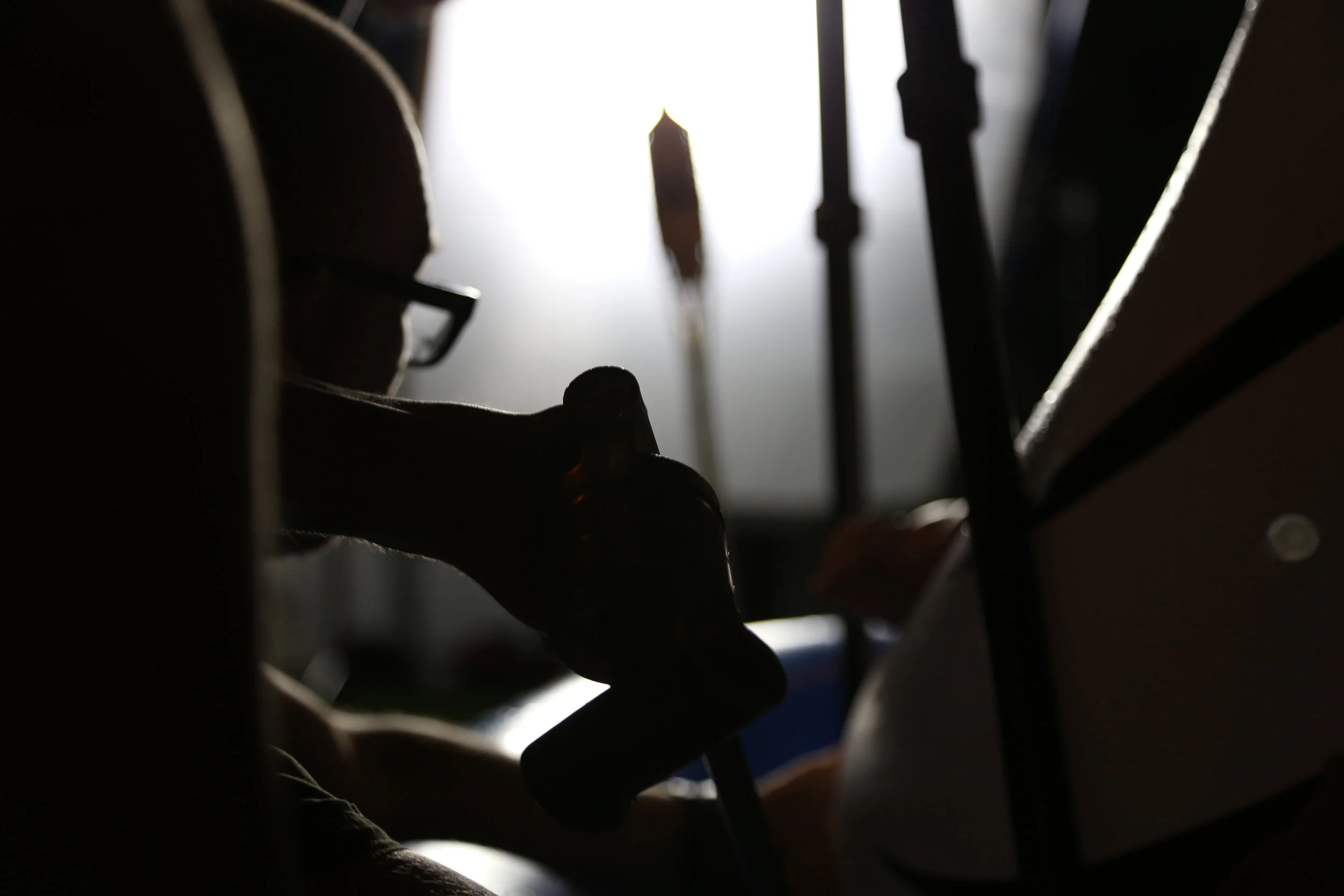 Silhouette of a hand adjusting or using a sewing machine, with bright light shining from behind, creating a contrast between dark and light areas.