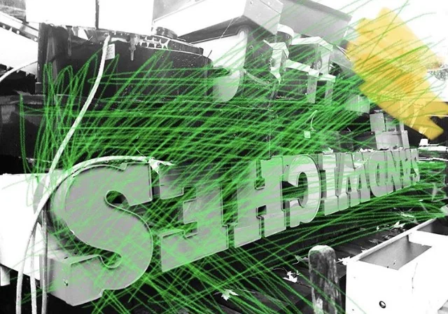 Close-up of a sign that reads "SELECT" with lines of green laser light crossing in front of it.