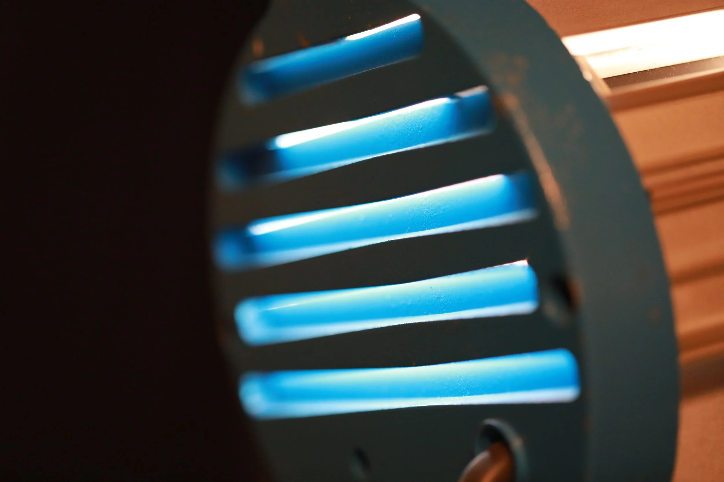 Close-up of a mechanical object with blue vent-like slats and black casing, possibly part of an electronic device.