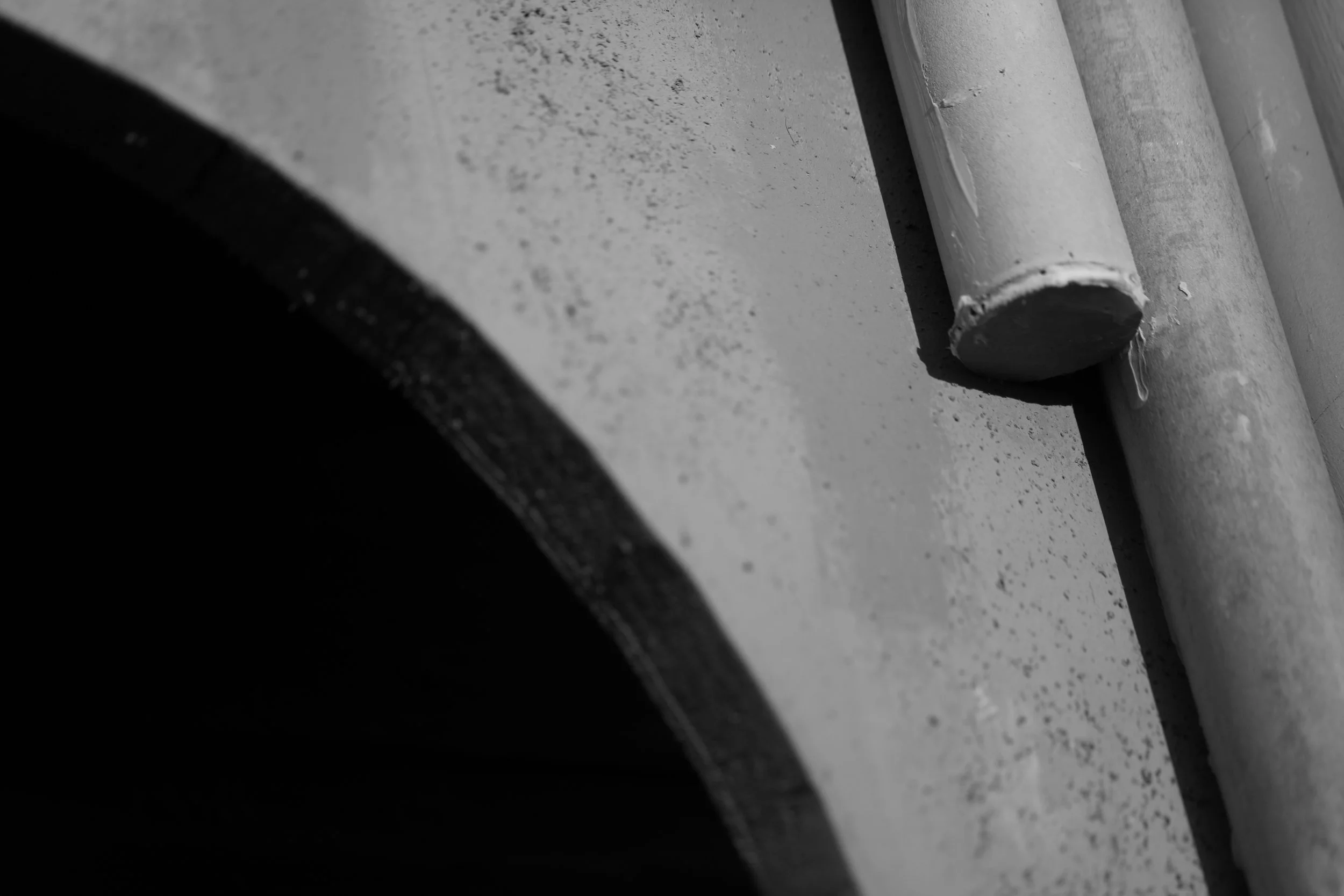 Close-up of a concrete wall with a metal pipe attached to it.