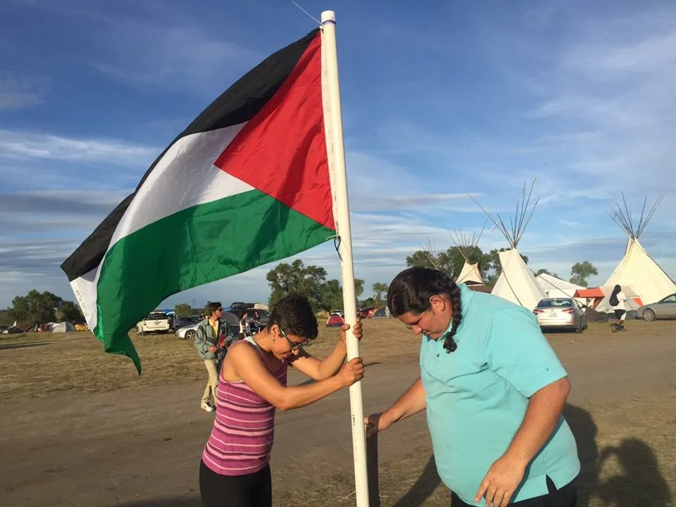 Mark Tilsen putting the Palestinian flag into the ground at Standing Rock camp in Sioux Country. (Photo credit: Friends of Salma)
