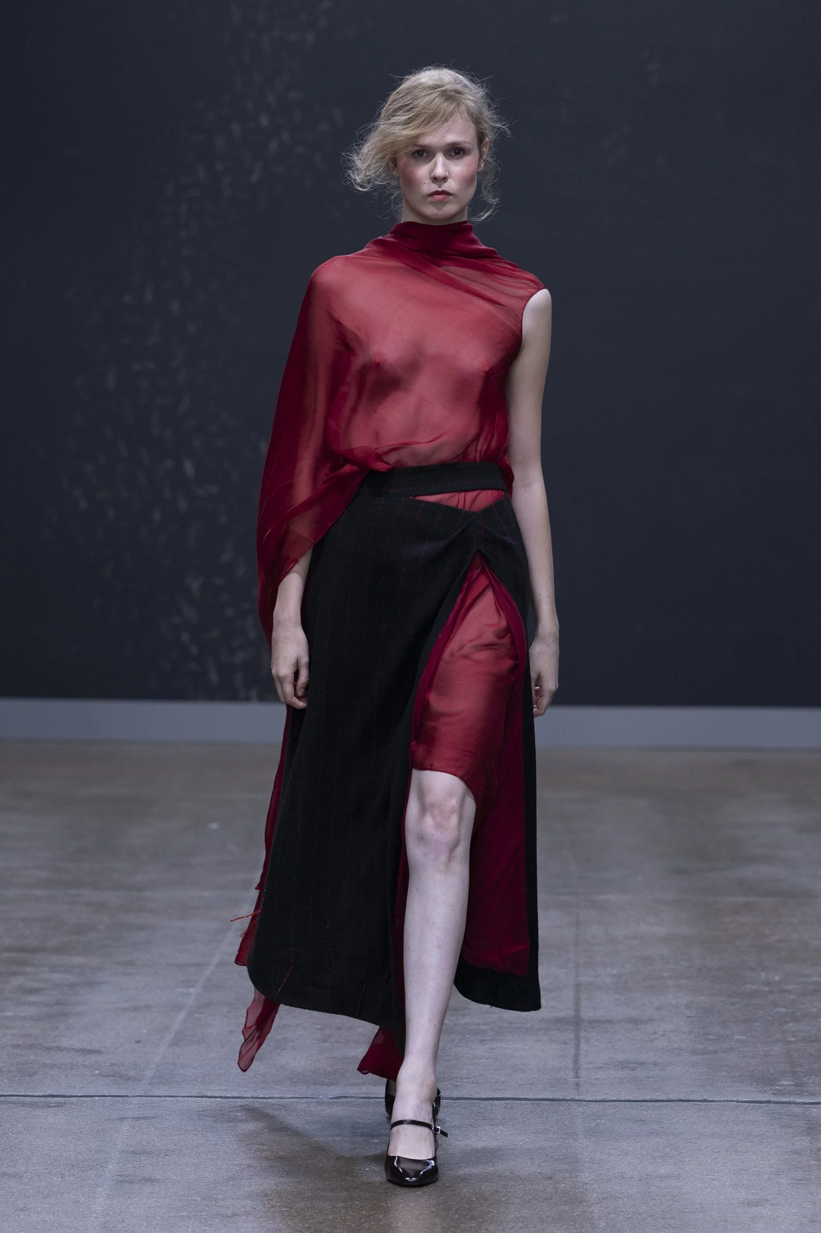 Model in a deep red and black asymmetric look closing ALISADUDAJ Silent Engravings at London Fashion Week SS26.