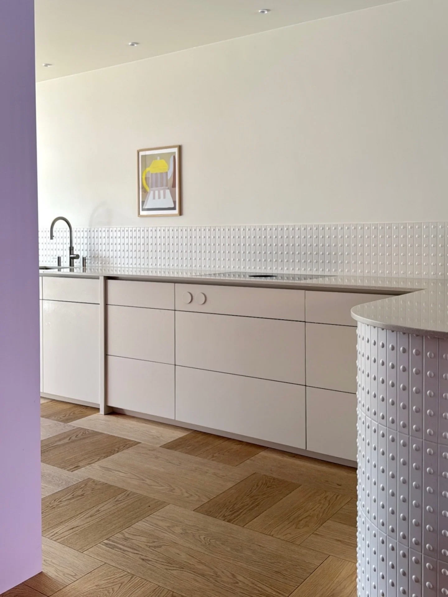 TEXTUUR &amp; RITME
Deze keuken is een spel van kleur, textuur en verhoudingen. Het lange aanrecht in zacht beige vormt een rustige basis tegenover een grote kastenwand in roze-lila. Het ritme van de tegels (Mutina) zorgt voor beweging, terwijl het H