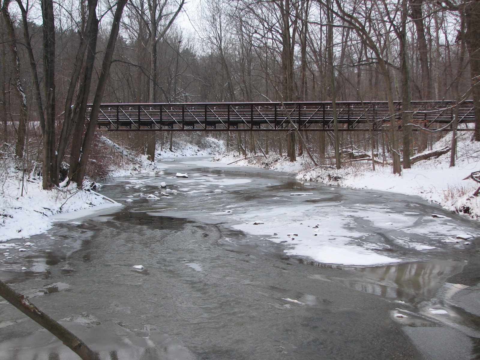 Pedestrian bridge from the snowy banks of the Beaver Creek