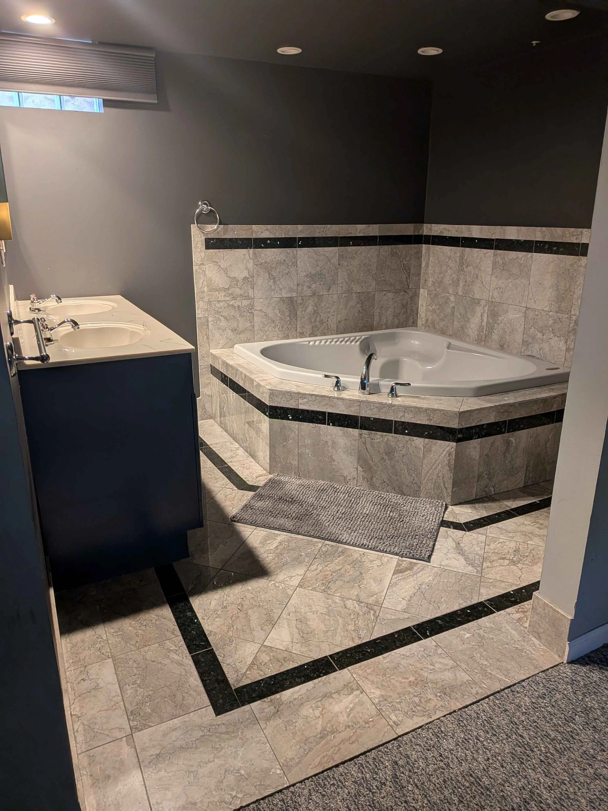 Interior view of a bathroom containing a vanity and jacuzzi.