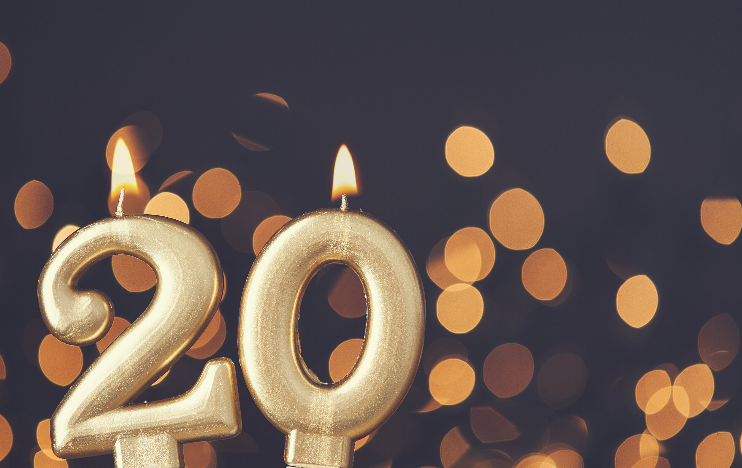 Gold number 20 celebration candle against blurred light background