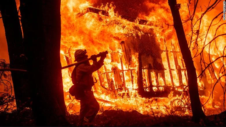 image from CNN / Firefighter Jose Corona sprays water as flames consume a house in Magalia, California.