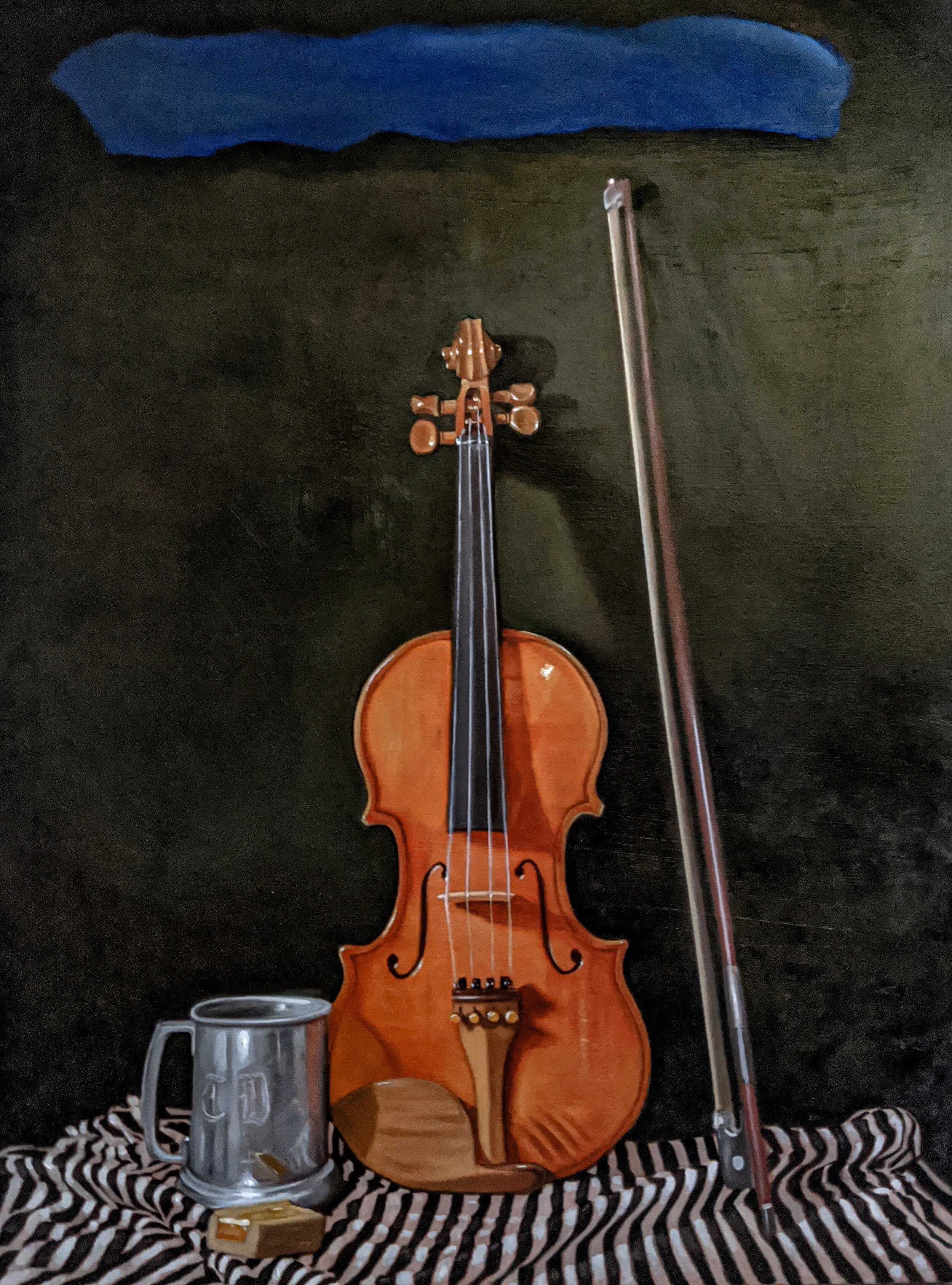 A wooden violin leaning against a dark wall, with a bow resting nearby and a metallic mug and a stick of rosen on the striped fabric surface below.