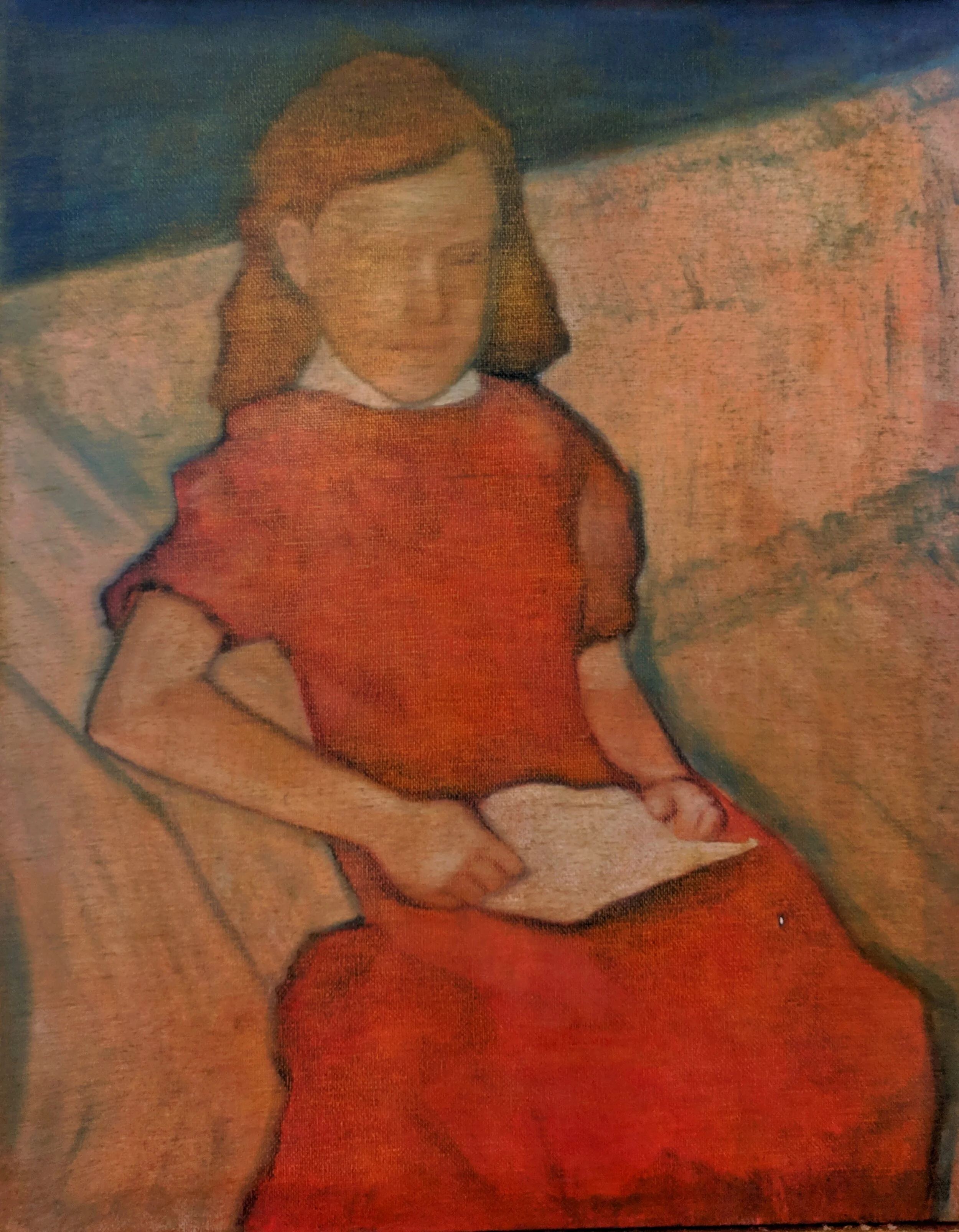 A girl in a red dress sitting on a sofa, holding a paper in her lap, with her left arm resting on the armrest.