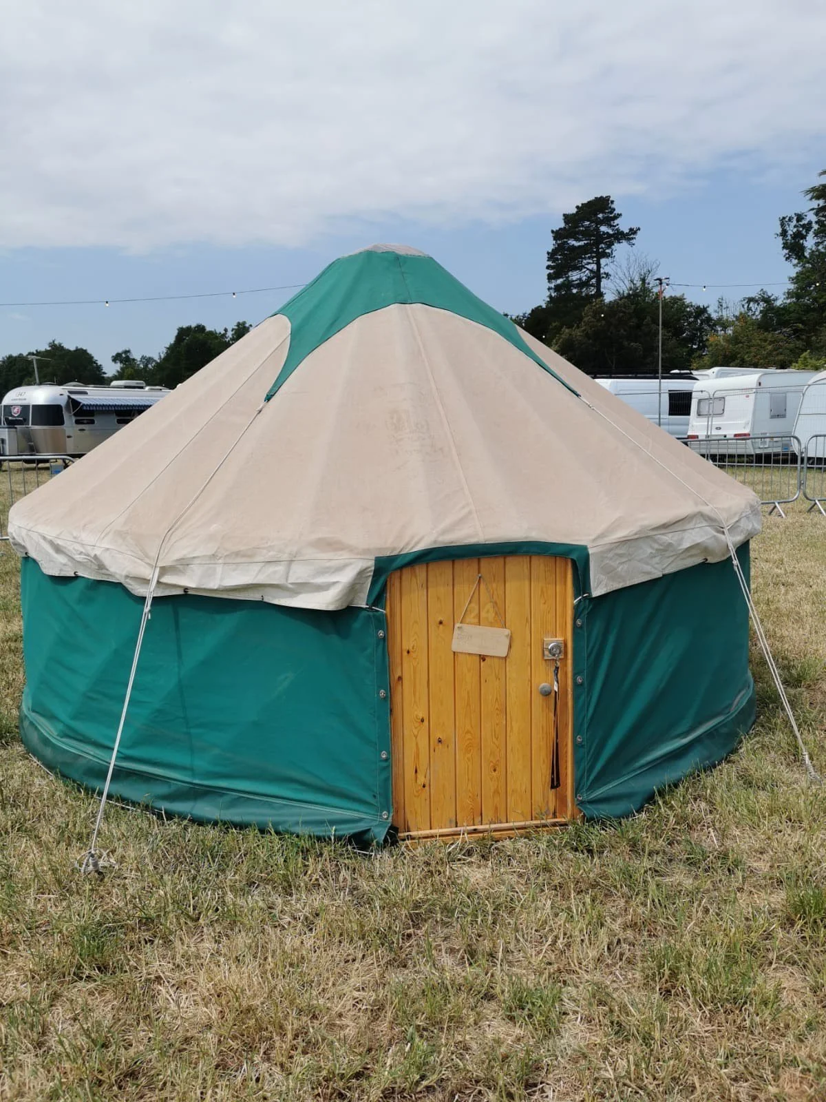 Traditional yurt rental exterior with solid wooden door and weatherproof canvas construction. Perfect family festival accommodation combining authentic design with modern camping comfort