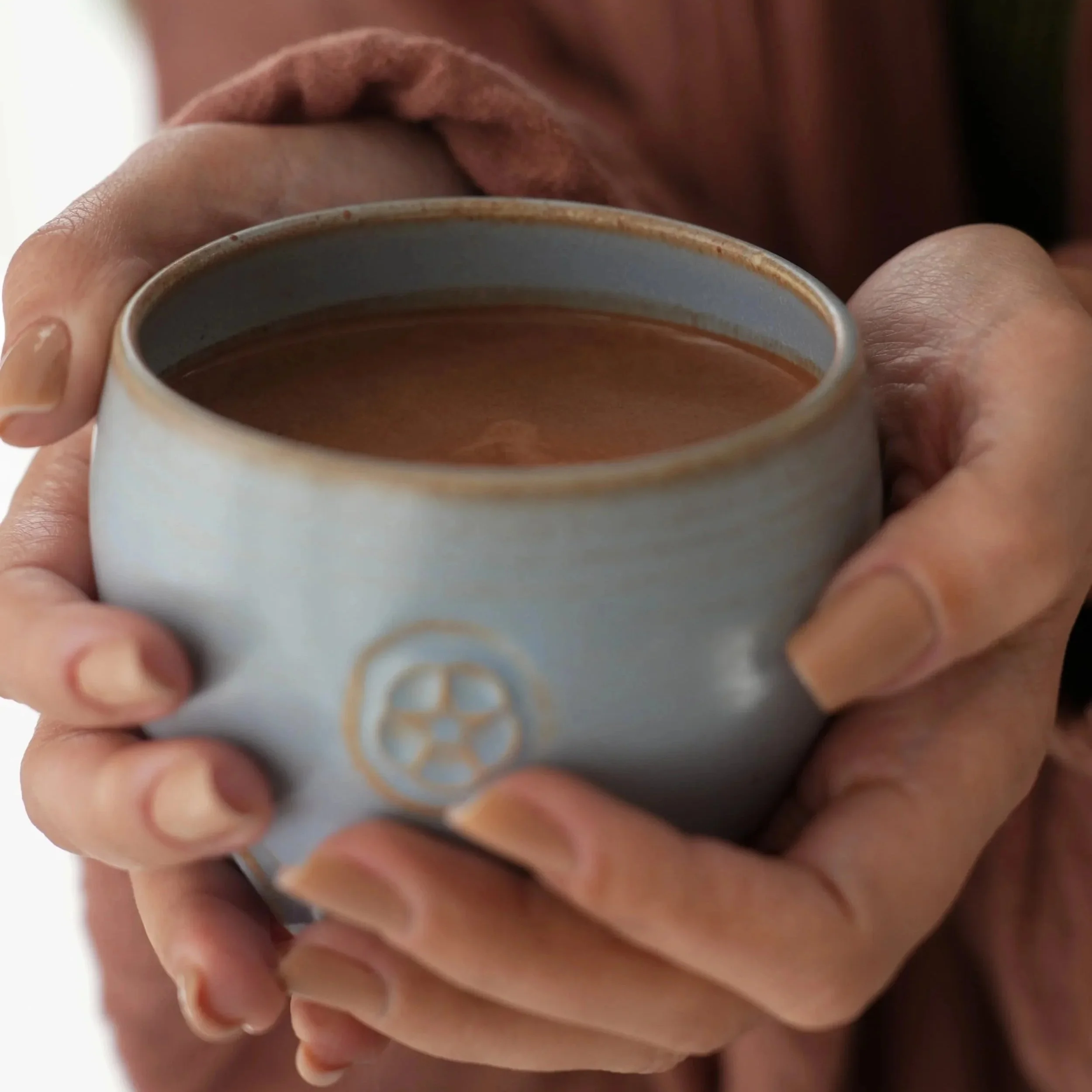 Woman holding hot cacao in a handmade ceramic cup for morning focus