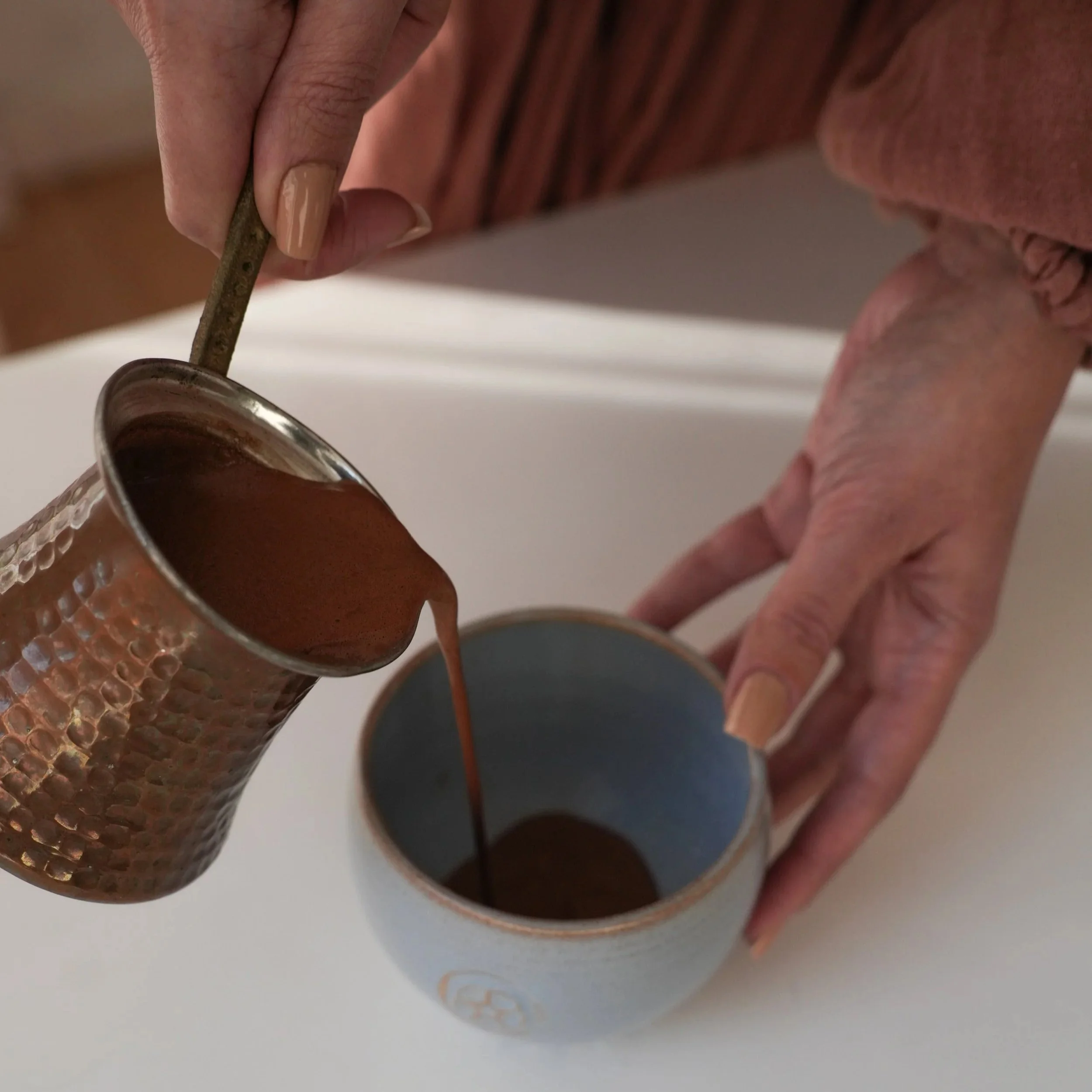 Woman pours cacao crumbles into ceramic cup for daily ritual