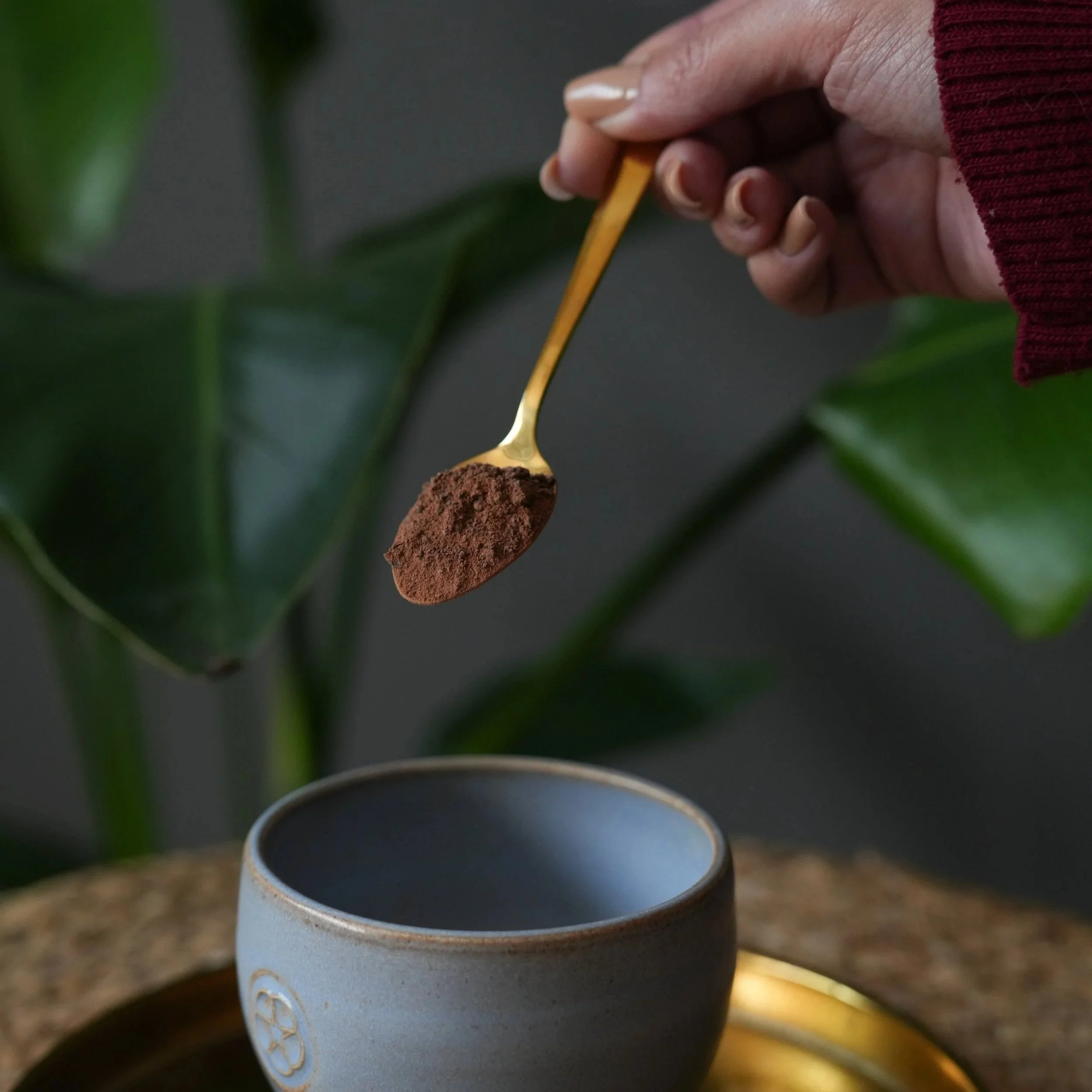 Woman pours cacao crumbles into ceramic cup for daily ritual