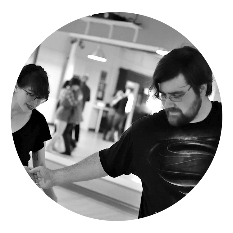 Black and white photo of a man partner dancing with a woman. Both look softly happy.