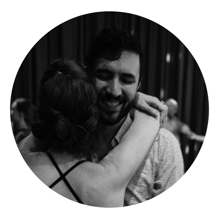 A black and white photo of a man smiling over the shoulder of his dance partner.