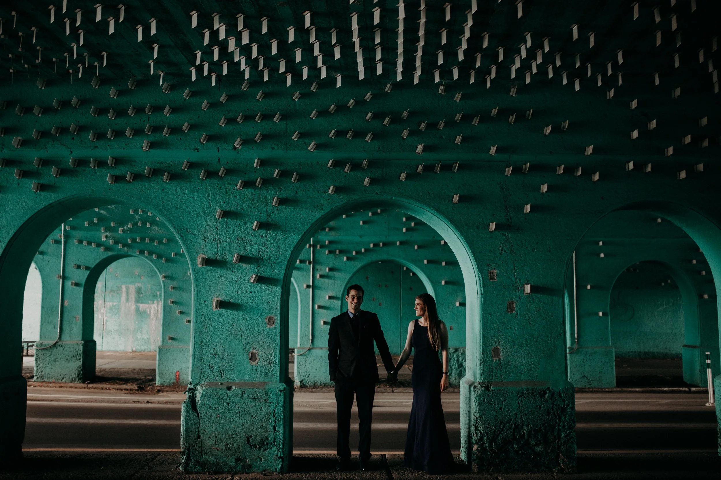 Guy and girl holding hands standing under Cass Ave Blue Underpass