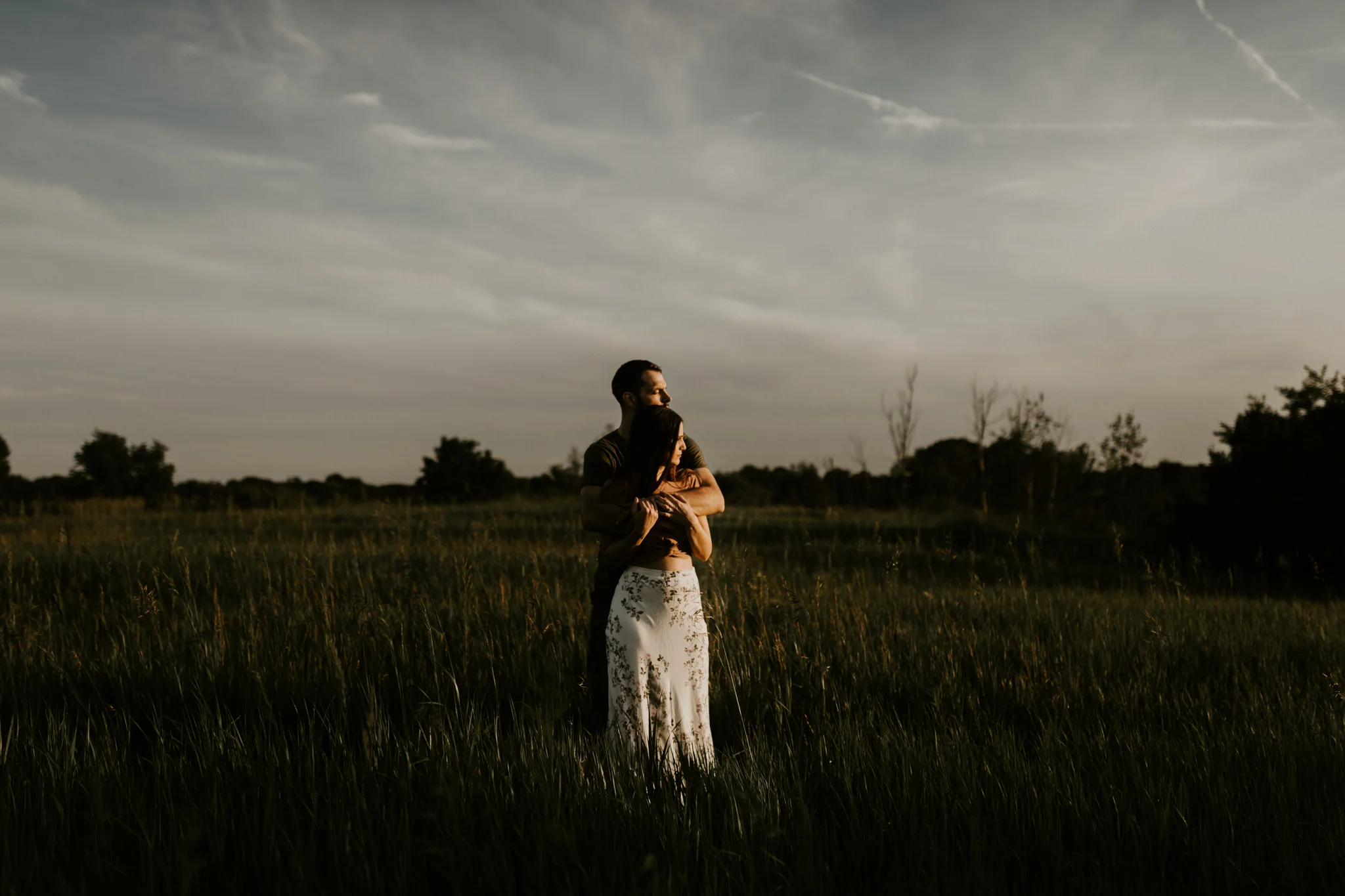 Couple standing, looking out at the sunset in Howell, Michigan