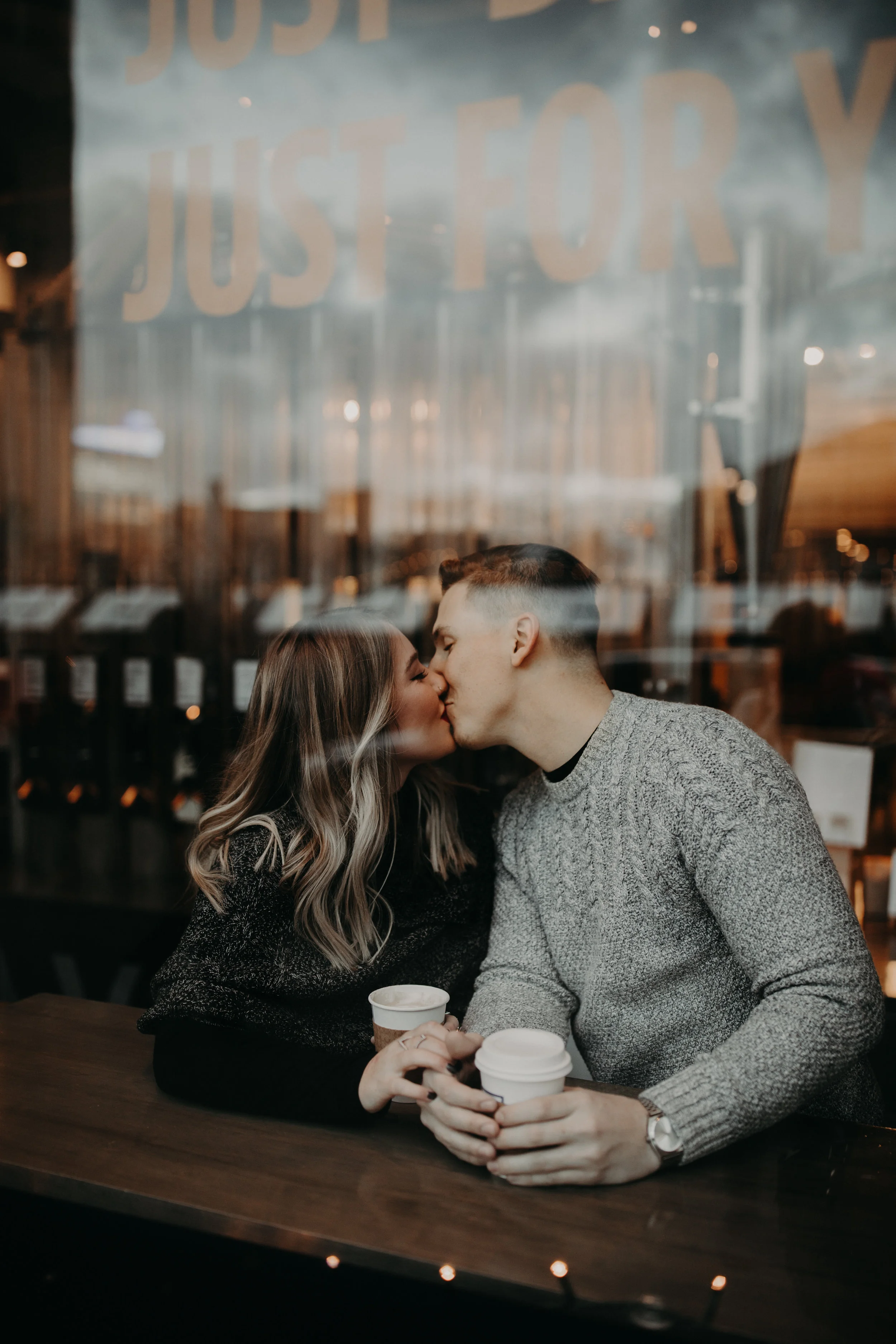 Couple kissing and holding coffee at Roasting Plant in Detroit