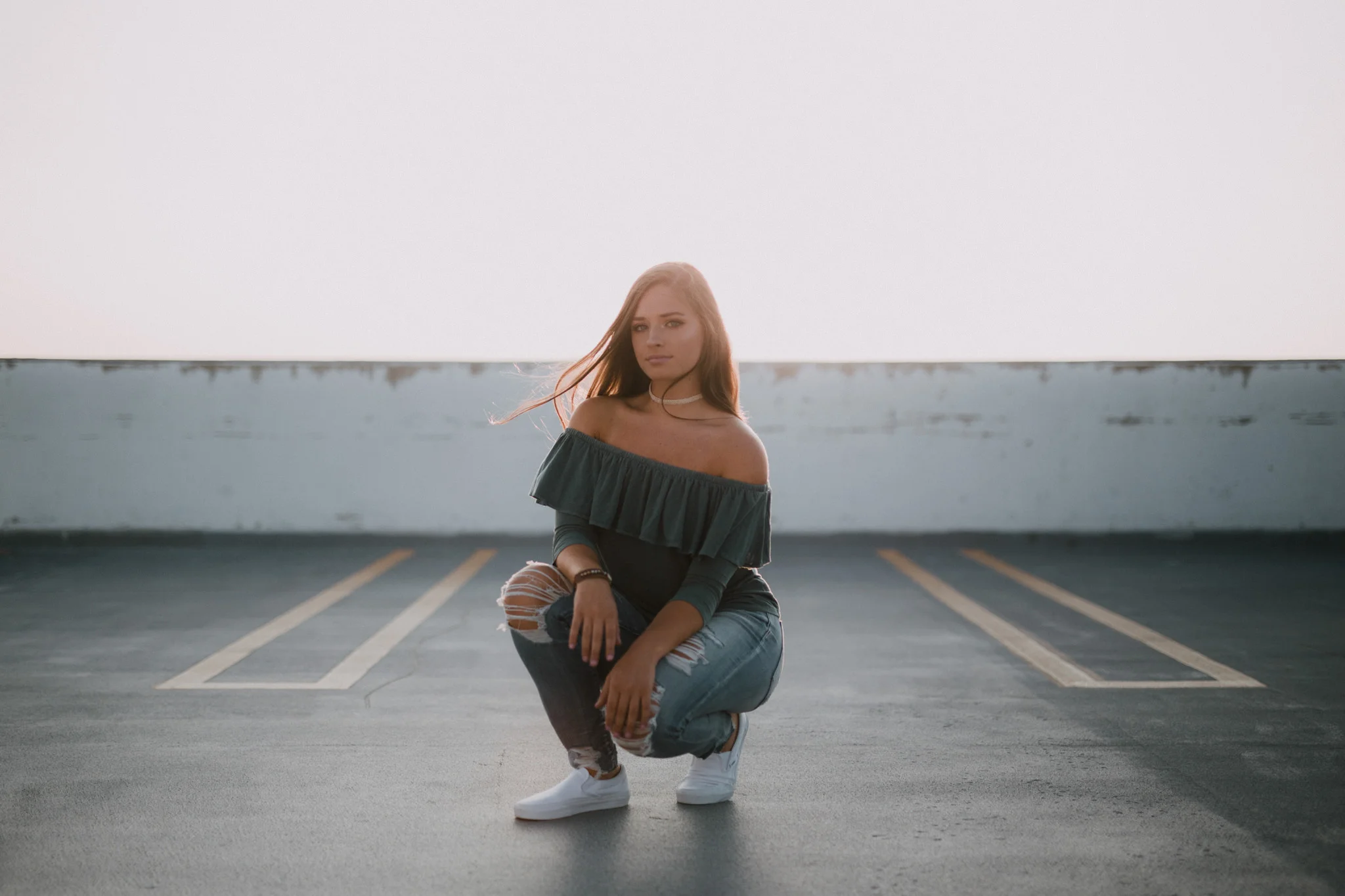 Girl in blue shirt and ripped jeans on parking garage