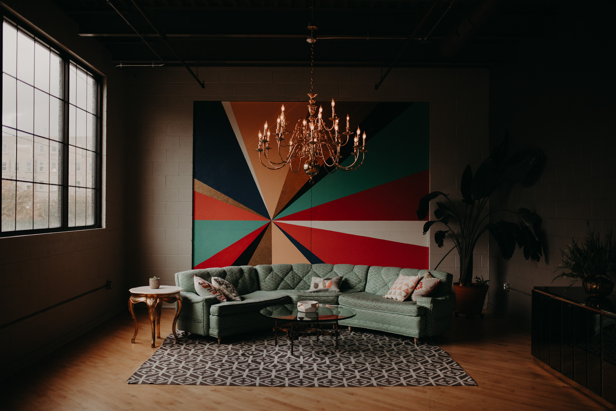 Rainbow mural with a blue couch and chandelier
