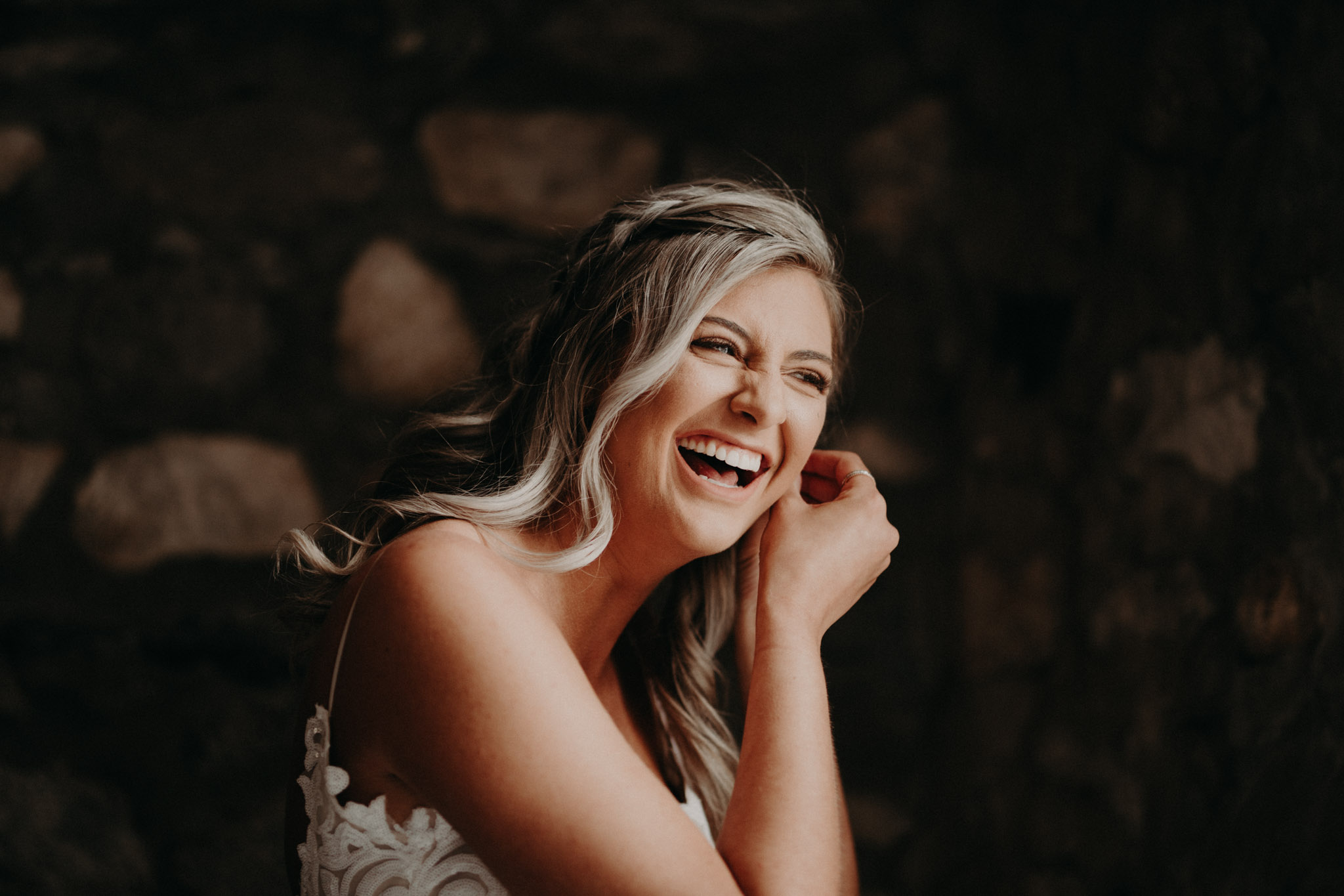 Bride laughing while putting earrings on