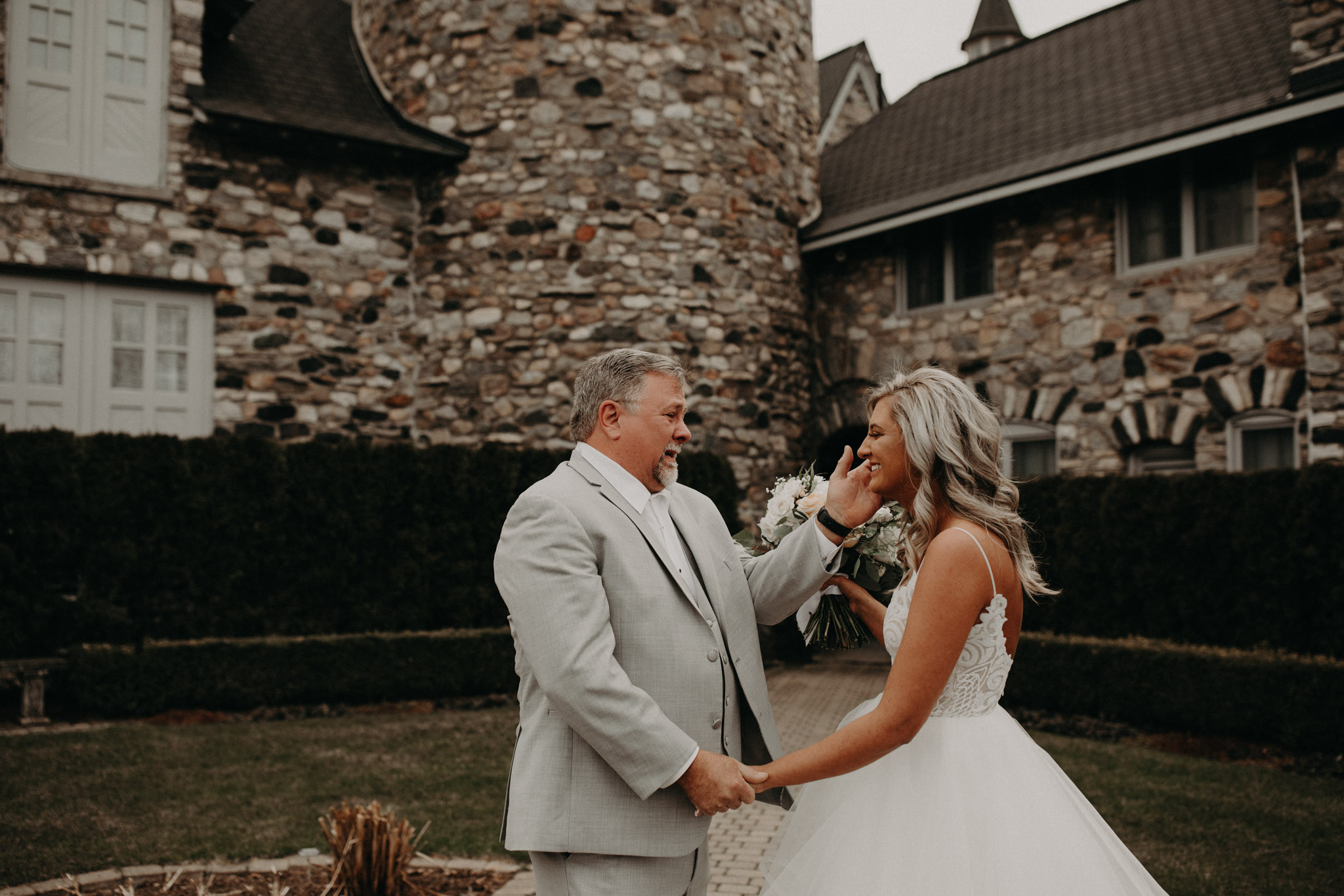 Bride and Dad first look in front of stone wall at Castle Farms