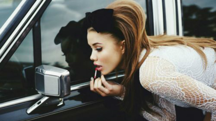 girl-looking-at-a-rearview-mirror-and-putting-a-lipgloss-on.jpg
