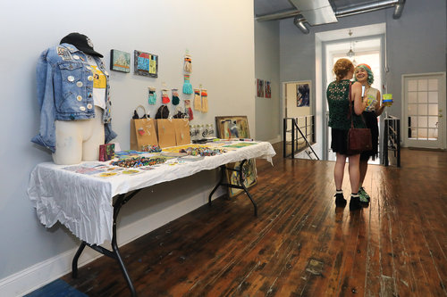 Artists Laura Little (left) and Alecia Vera Buckles (right) standing by the " Swag " table at OFFLINE. Artists were encouraged to produce miniatures in the style of their typical work to encourage sales and generate hype for the show. 