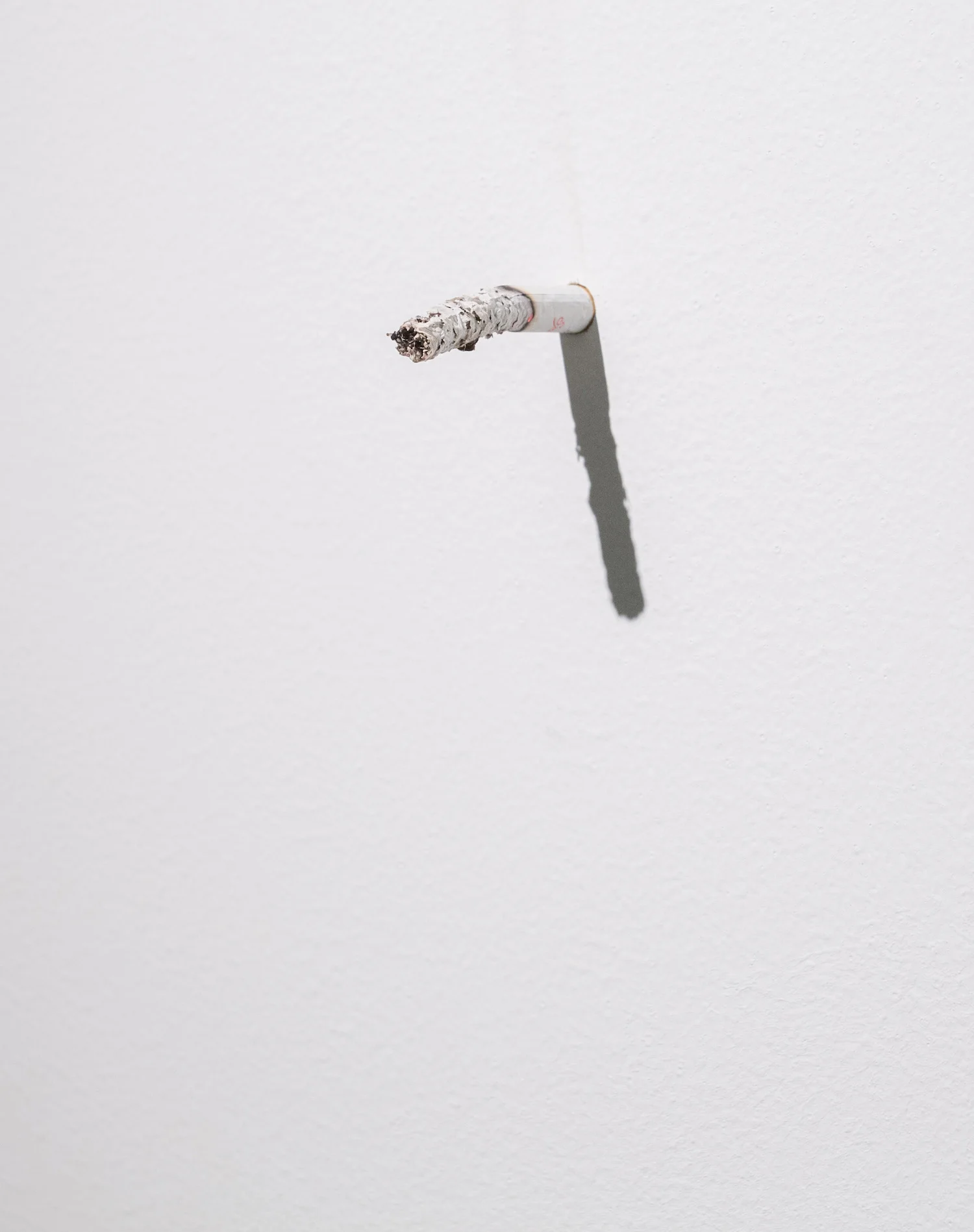 Parler à un mur (detail) 2011 Cigarette Variable dimension During the exhibition, the gallerist smokes his cigarette with the white wall of the exhibition space.