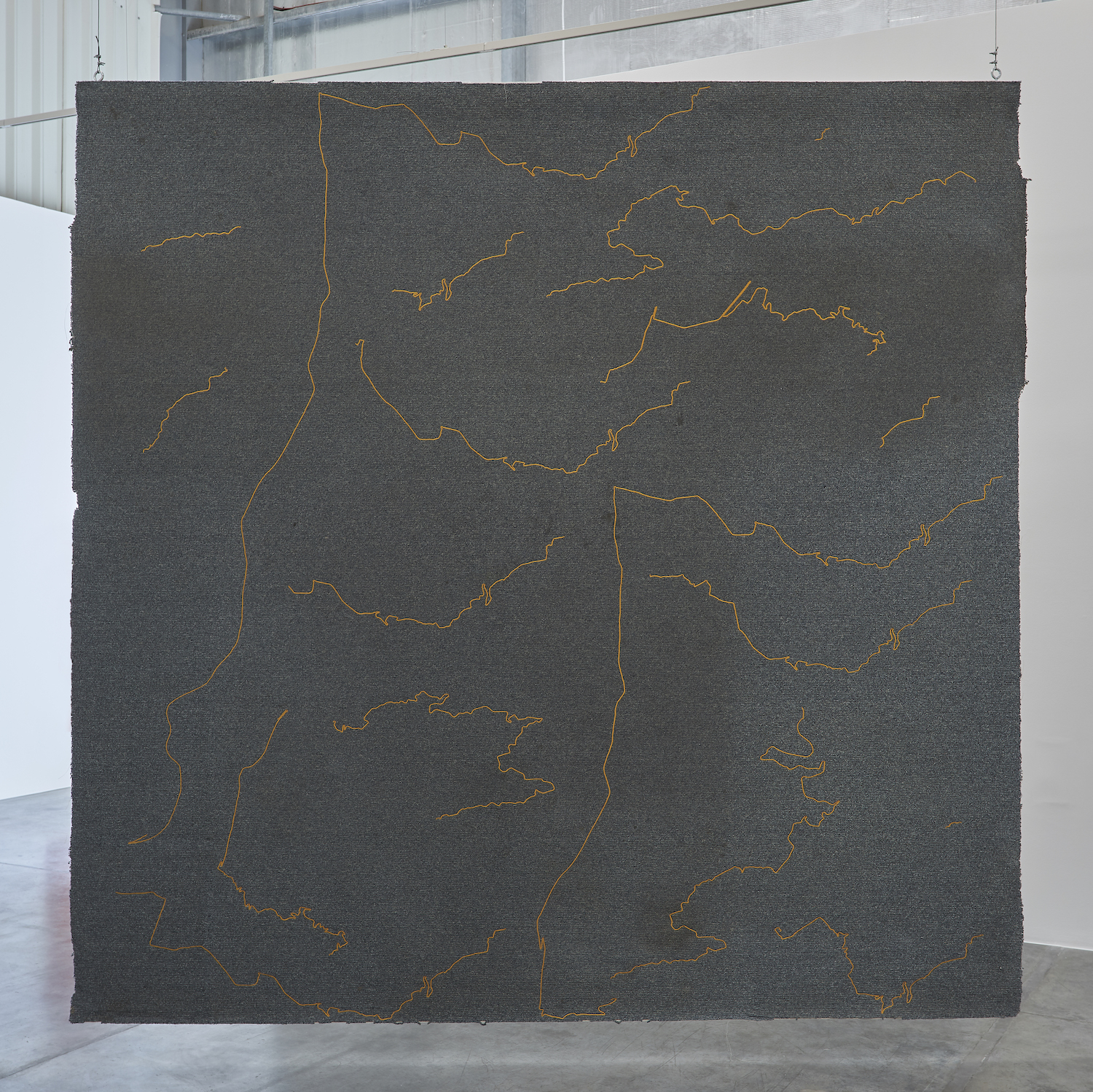 The Encounter of the First and Last Particles of Dust 2019 Used carpet, gold thread embroidery 333.5 x 336.5 cm The carpet of the room which the artist occupied as a teenager, from 1995 to 2001, is torn off and embroidered with the 18 most significant trajectories underwent during this time span.