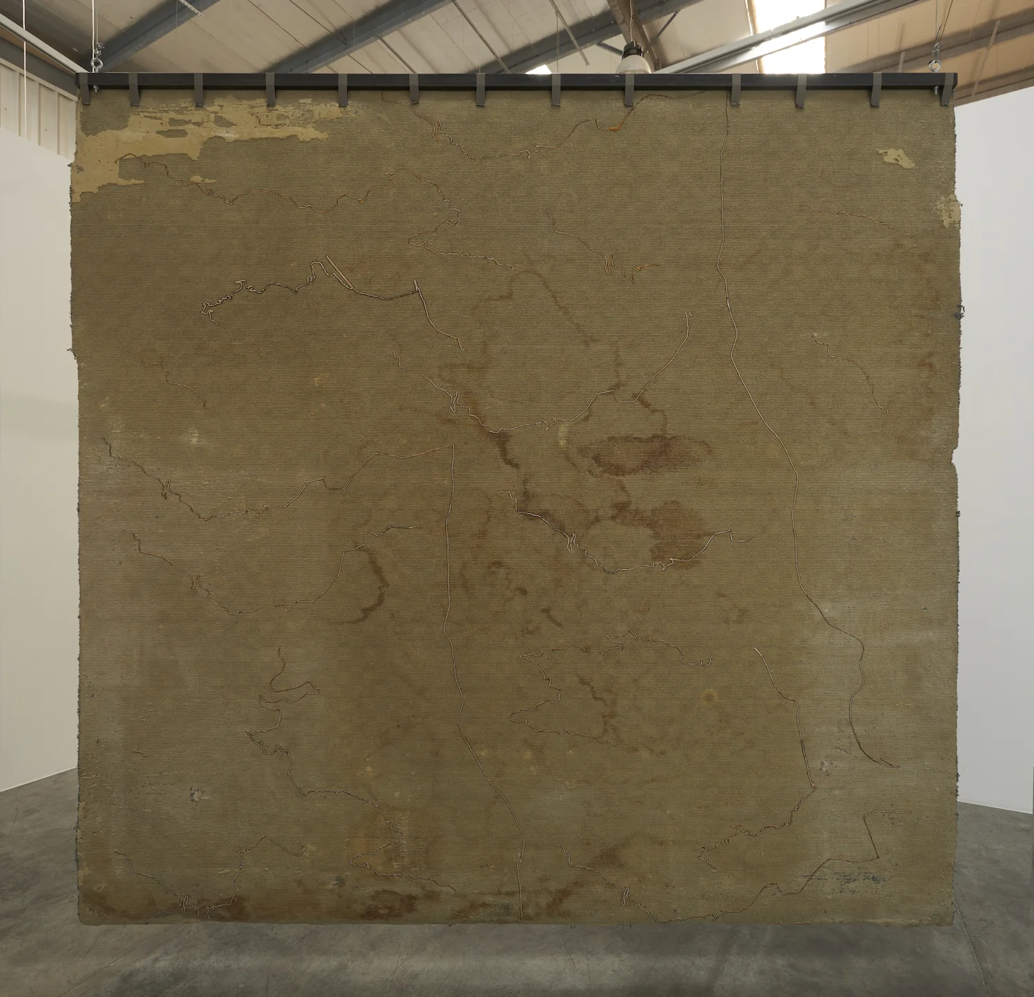 The Encounter of the First and Last Particles of Dust 2019 Used carpet, gold thread embroidery 333.5 x 336.5 cm The carpet of the room which the artist occupied as a teenager, from 1995 to 2001, is torn off and embroidered with the 18 most significant trajectories underwent during this time span.