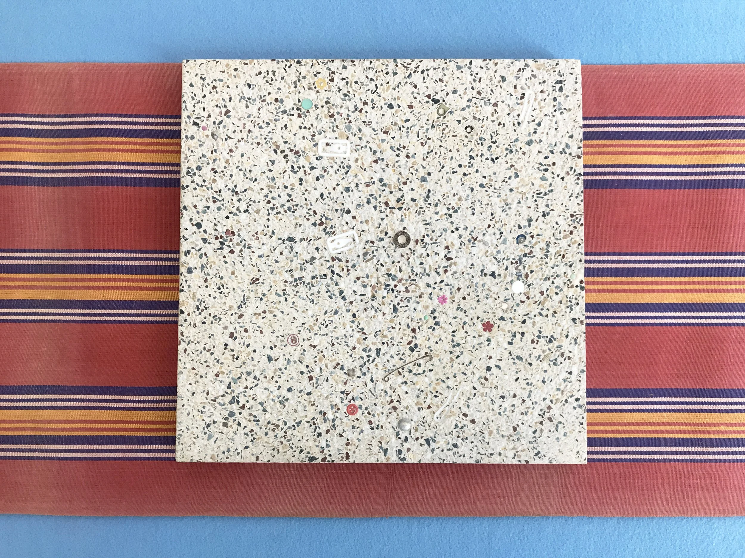 Terrazzo conundrum, 2020, Terrazzo tile with fingernails, collected stones, seeds and fake gold earing, 30 x 30 cm