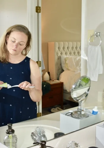 previously spirited middle aged woman woefully applies toothpaste to a toothrbush whilst dreaming of a brand new kitchen that may never be