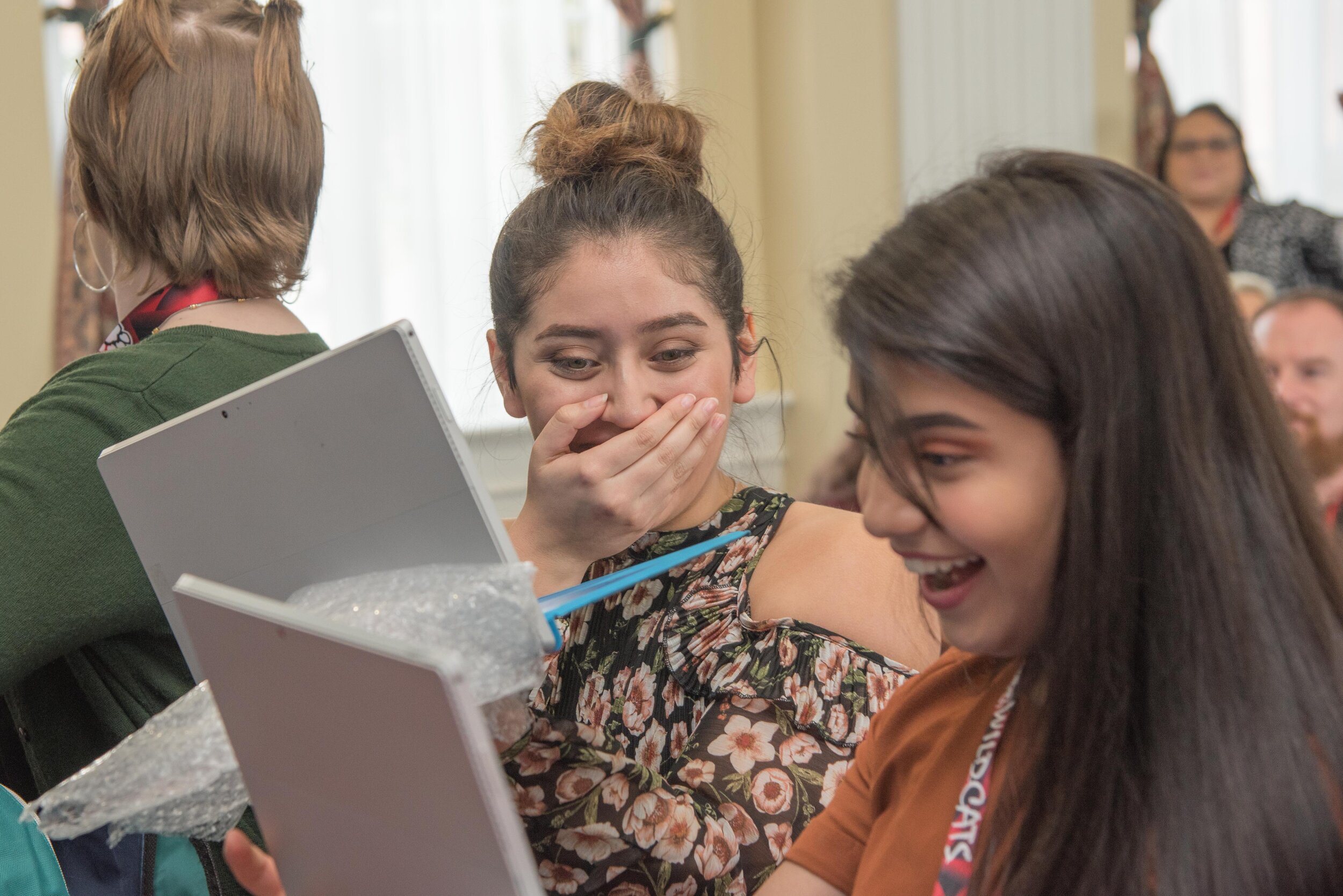  Michelle J. and Jackie A. react with delight as they receive their surprise gift of Surface tablets. 