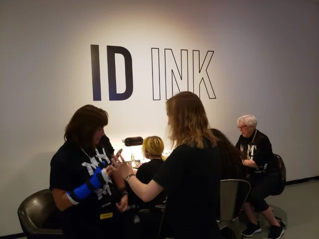 You could get your arm inked with the ID logo or another related design. (Kathy Kenda is seated to the right in the background.)