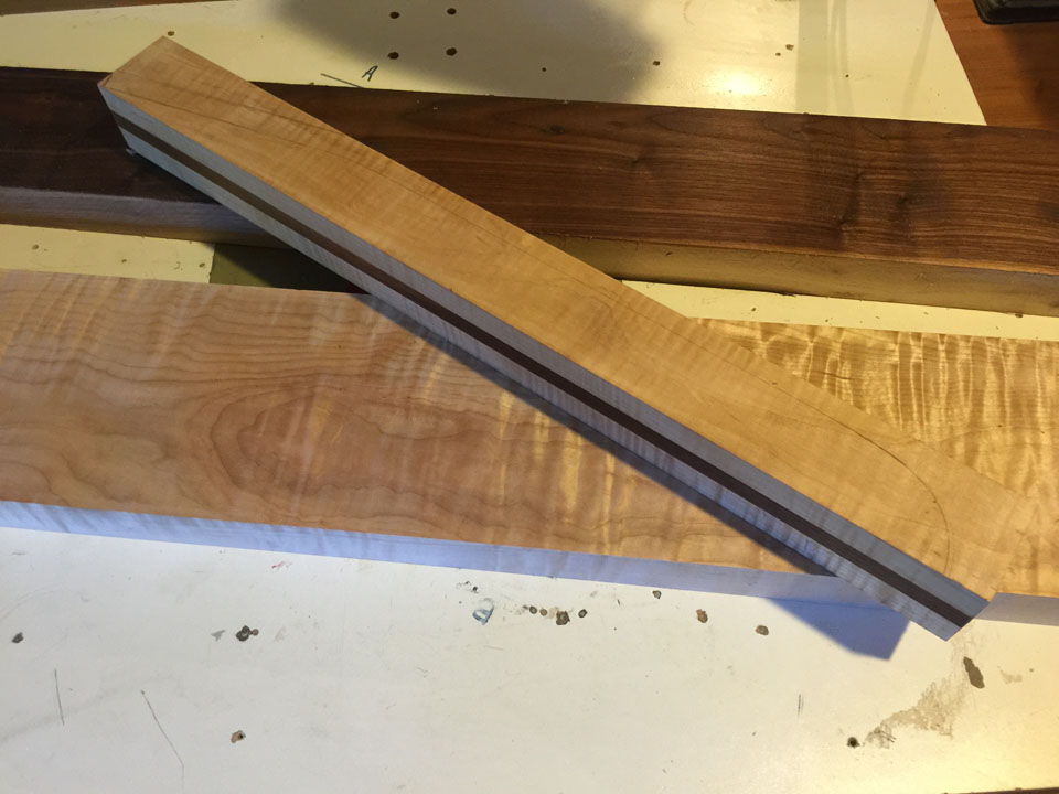 A NECK BLANK IS LAMINATED FROM TWO HARD MAPLE STRIPS WITH A HARD WALNUT CENTER STRINGER.