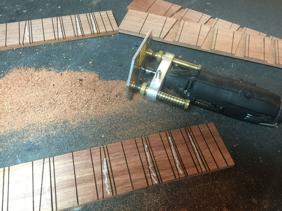 FRET SLOTS ARE CUT WITH A SPECIAL SAW, THEN THE SIDES OF THE TRIANGULAR FRET MARKERS ARE SLOTTED. THE FRET MARKER AREAS ARE CUT OUT BY HAND WITH A MINIATURE ROUTER.