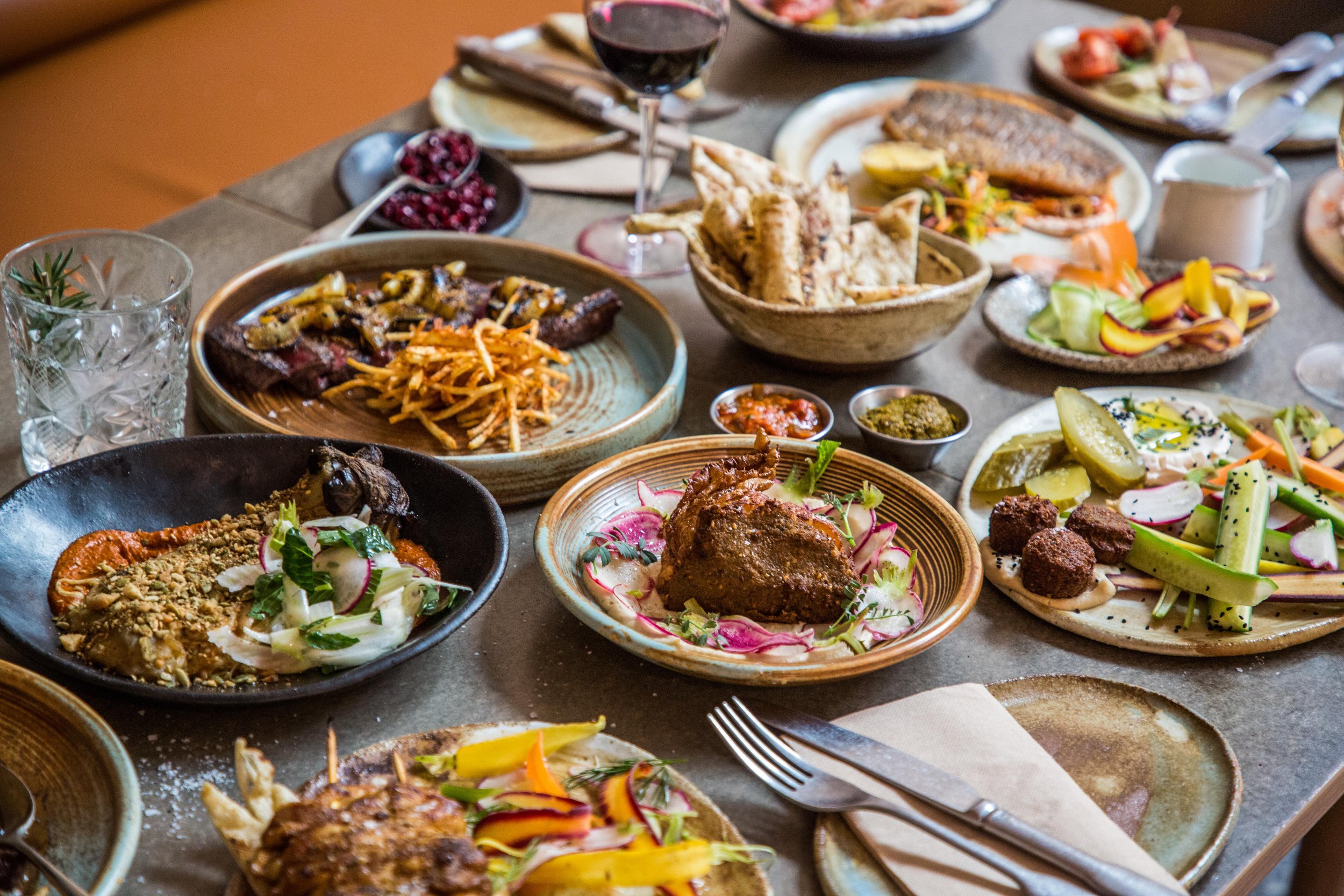  Table full of Middle Eastern food. Meat, fish, cauliflower, fattoush salad. Best restaurant in Sydney 