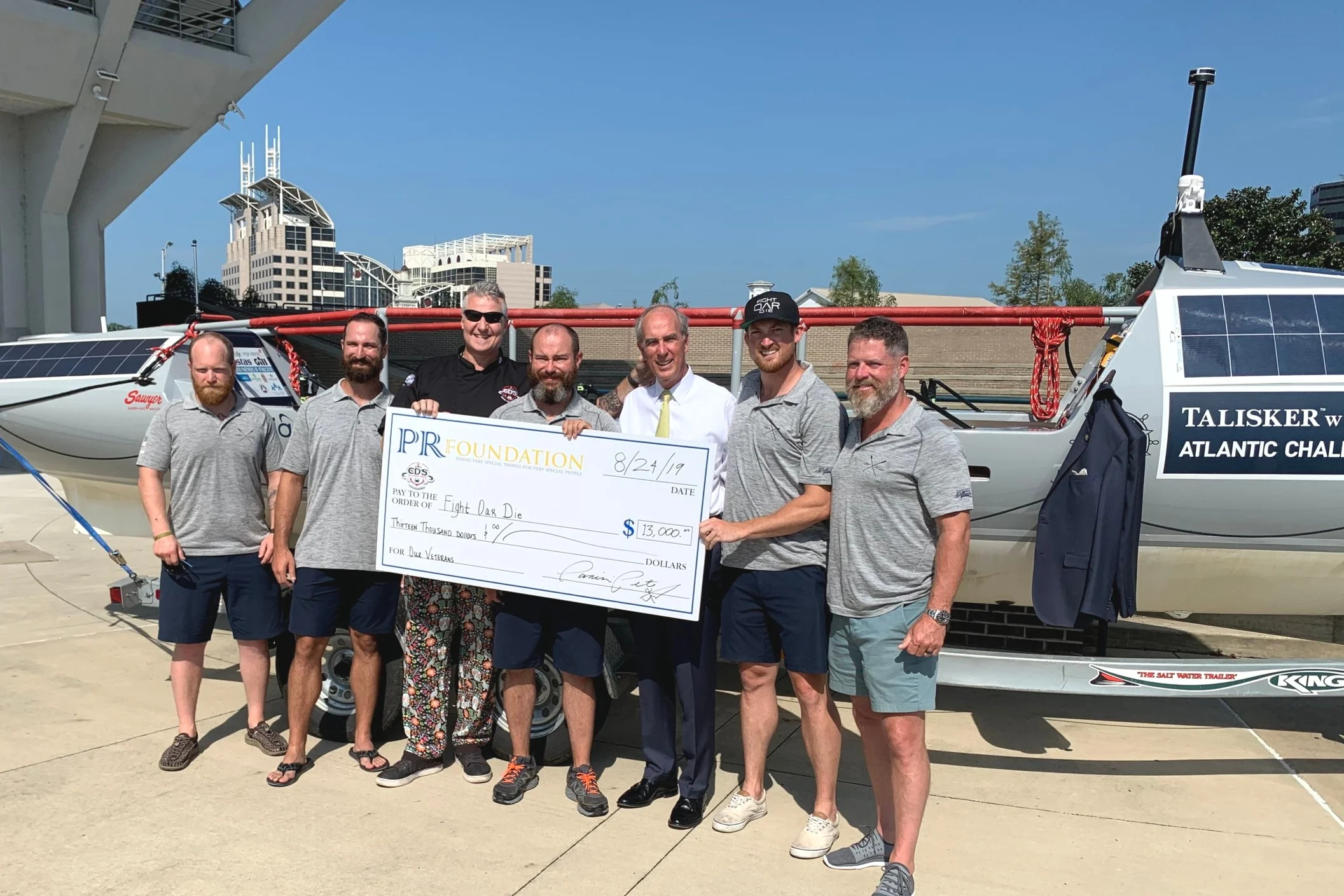 2019 PR Foundation co founder Panini Pete Blohme presenting a check for $13,000 to support the Fight Oar Die Military Veteran Team crossing the Atlantic in their boat Woobie in the Talisker Whiskey Challange .Fight Oar Die is made up of veterans from various Army backgrounds, ranging from Infantry Paratroopers, US Army Rangers and US Special Forces raising awareness of the issues veterans and their families face after they return home from combat deployment – things like Post-Traumatic Stress Disorder (PTSD), Traumatic Brain Injuries (TBI) and reintegration issues.