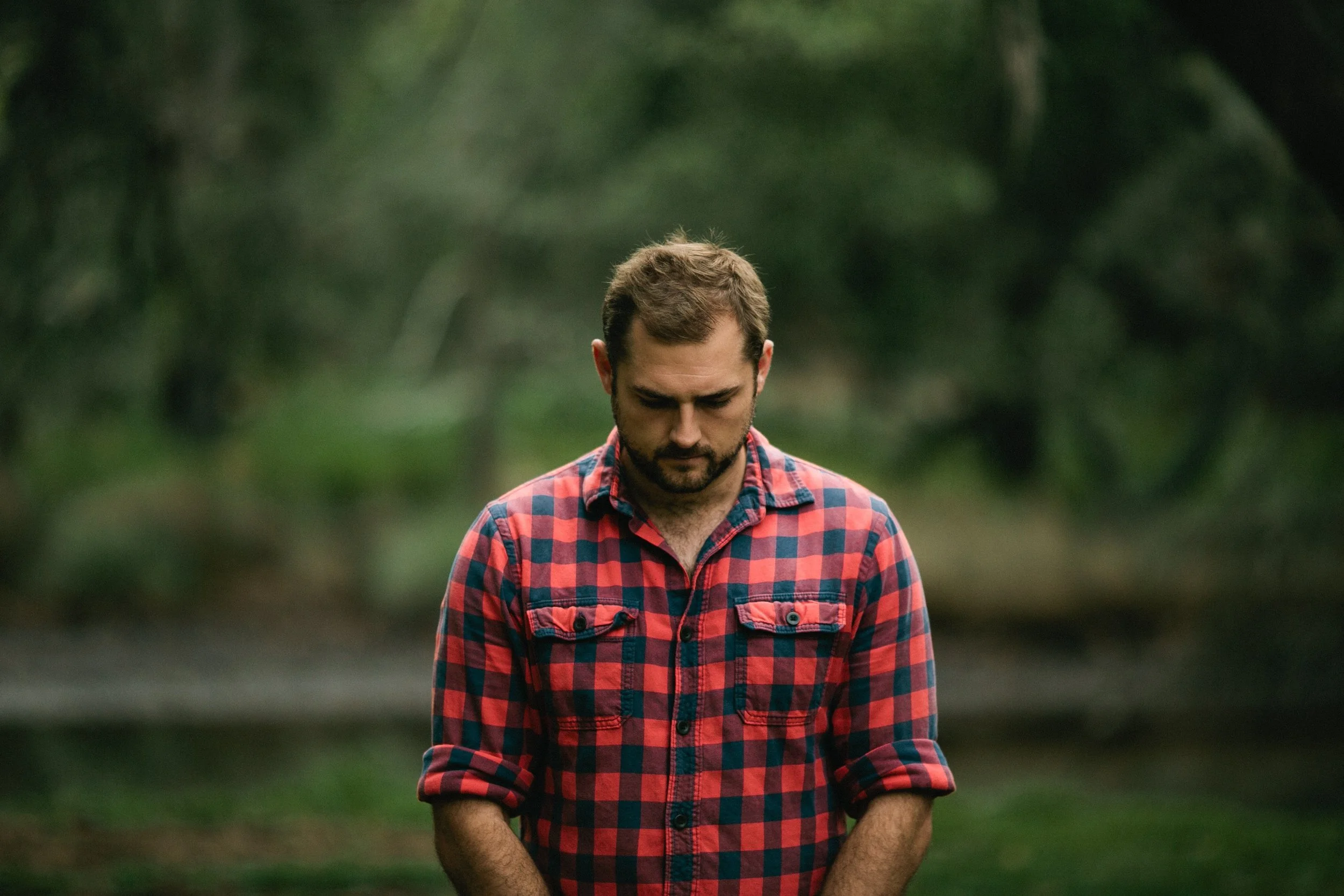 sensitive emotional bearded man with plaid shirt looking downward