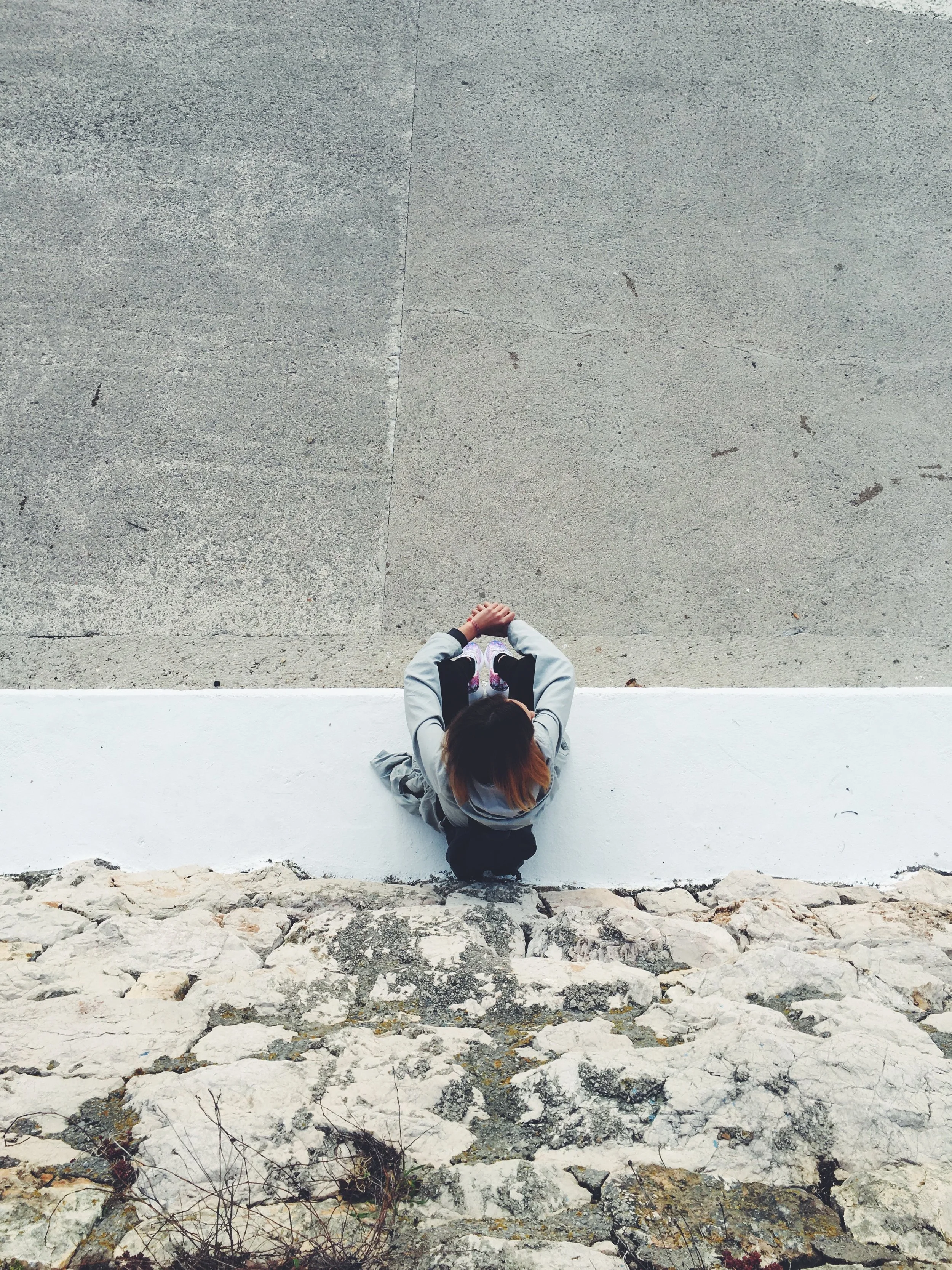 aerial shot of an anxious woman sitting on a ledge