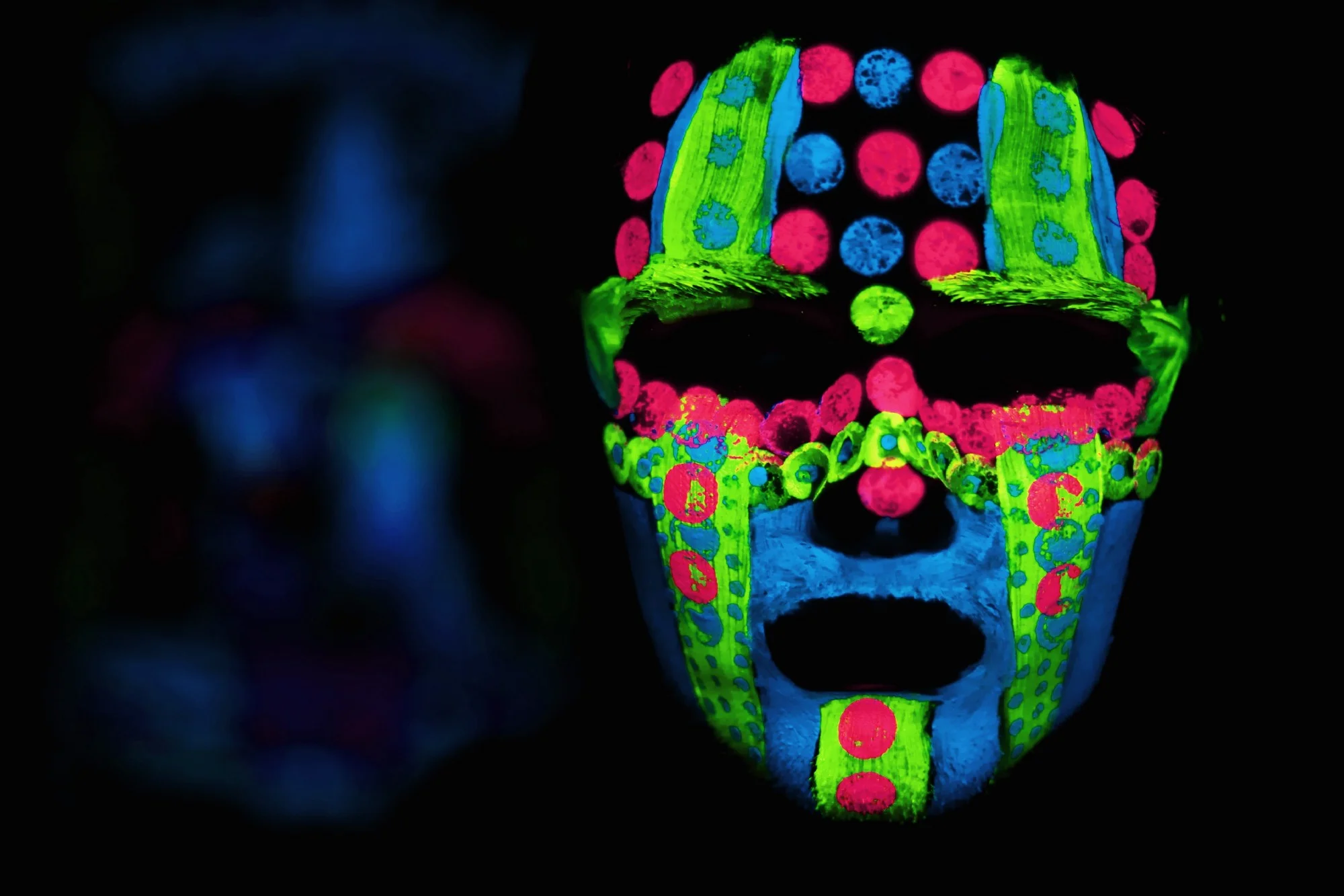 man's face in the dark with neon multicolored paint
