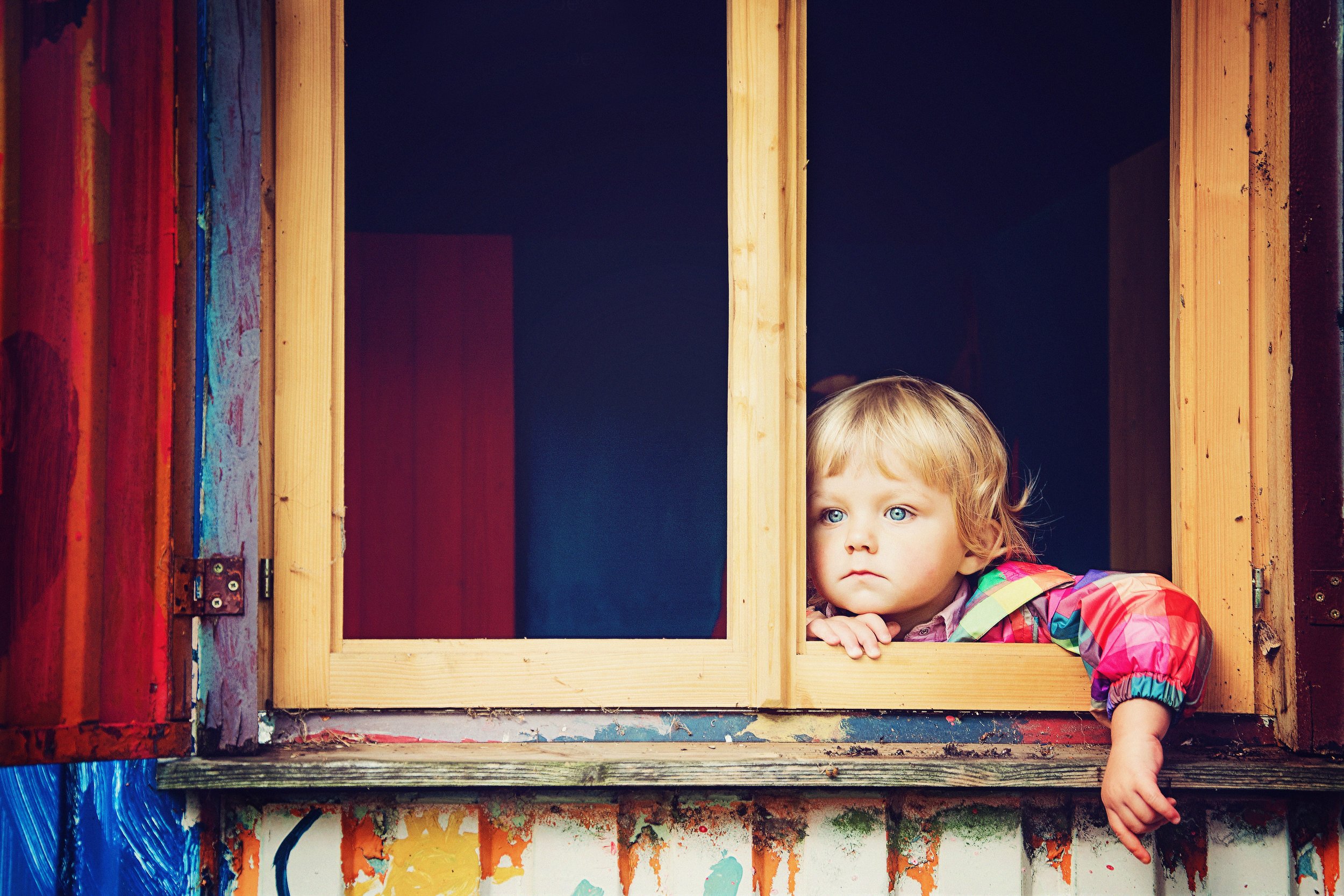 anxious OCD child with distant expression looking out window of house