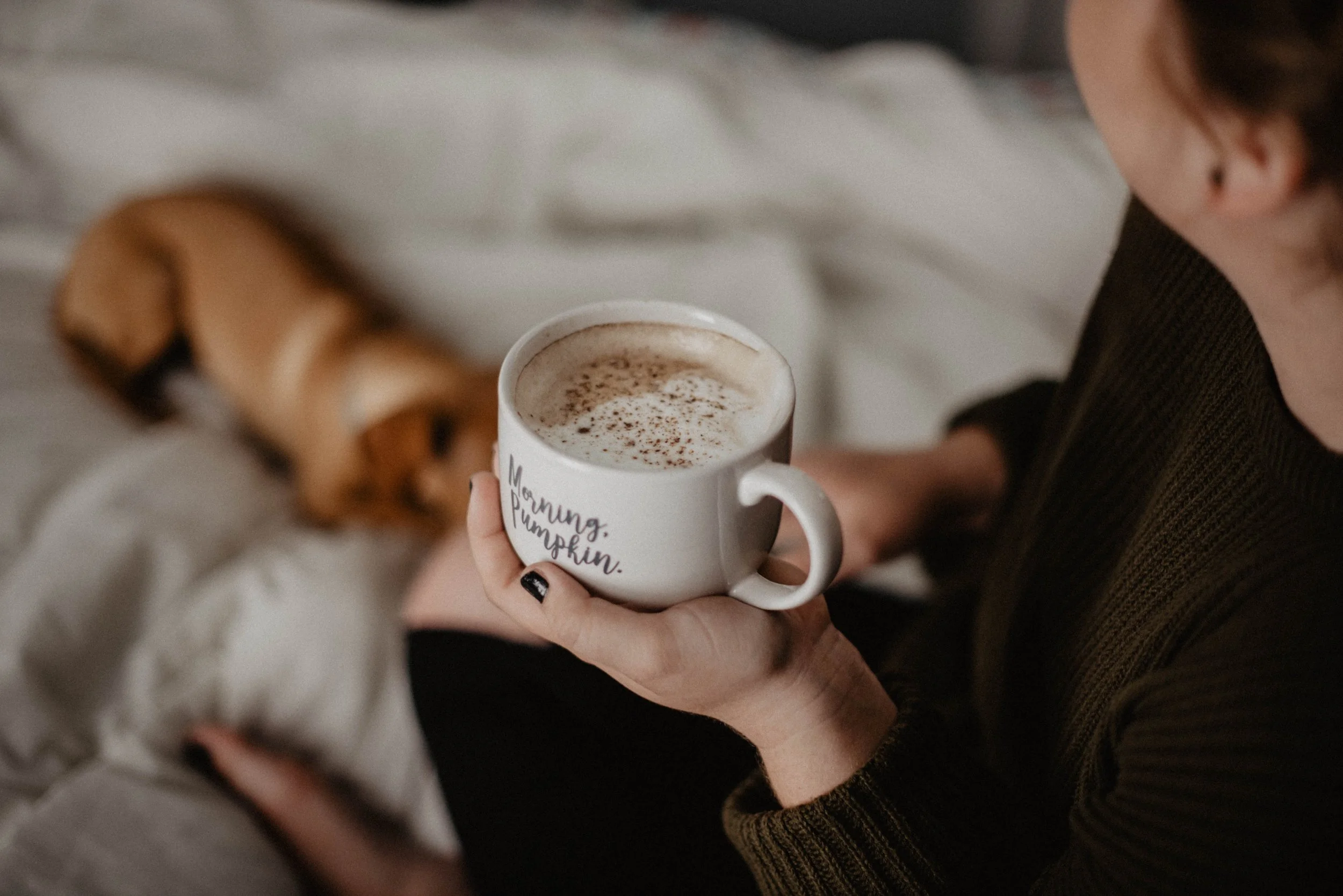 woman caring for mental health by sitting on couch with coffee cup and dog
