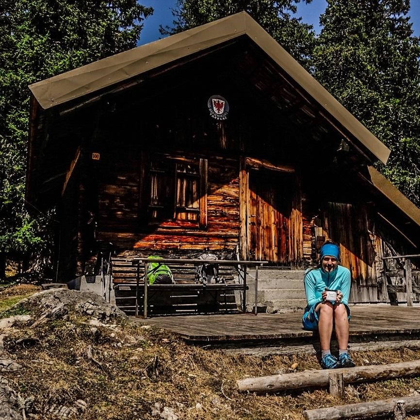 Sarah Hudson holding mug sitting in front of cabin