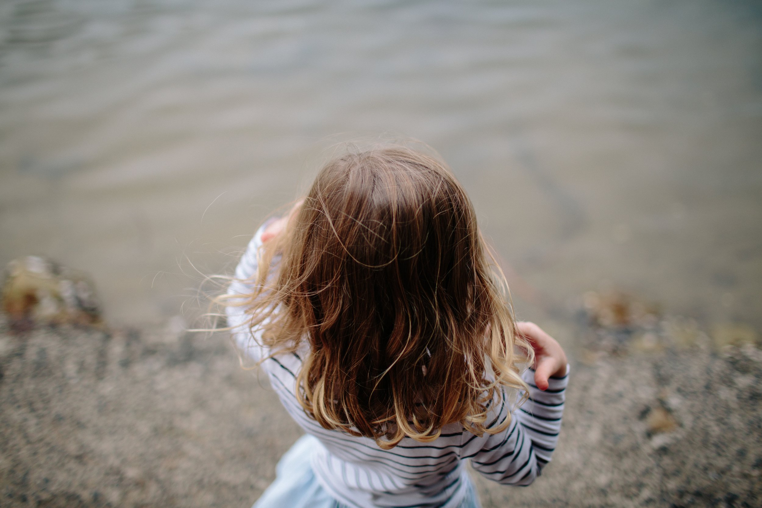 little girl who survived childhood trauma looking down at water