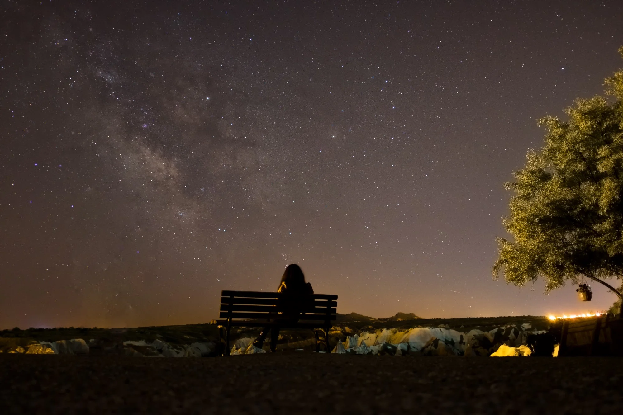 lonely woman sitting on park bench beneath starry sky