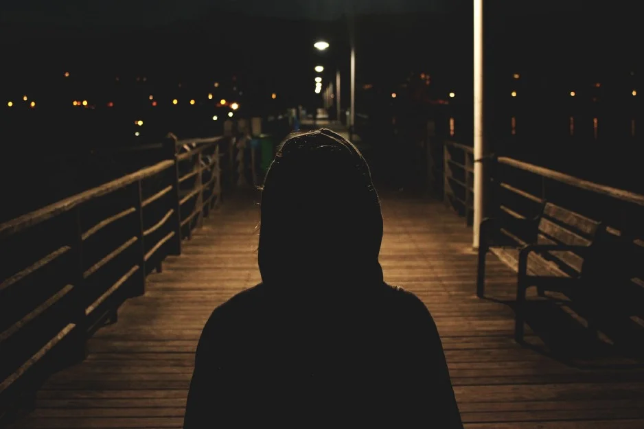 anxious person walking on boardwalk at night